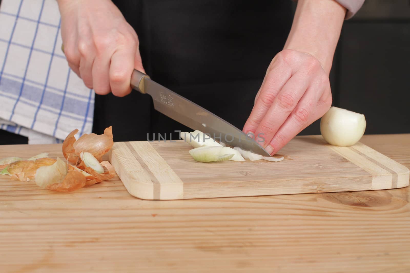 Freshly washed white onion on cutting board with knife.