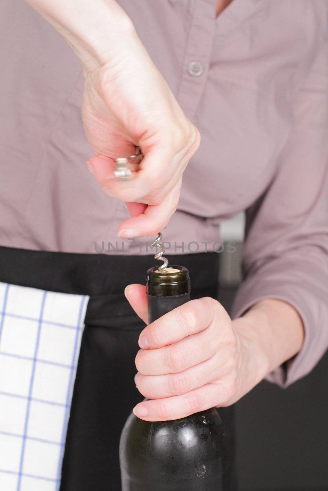 Opening a wine bottle with corkscrew in a kitchen