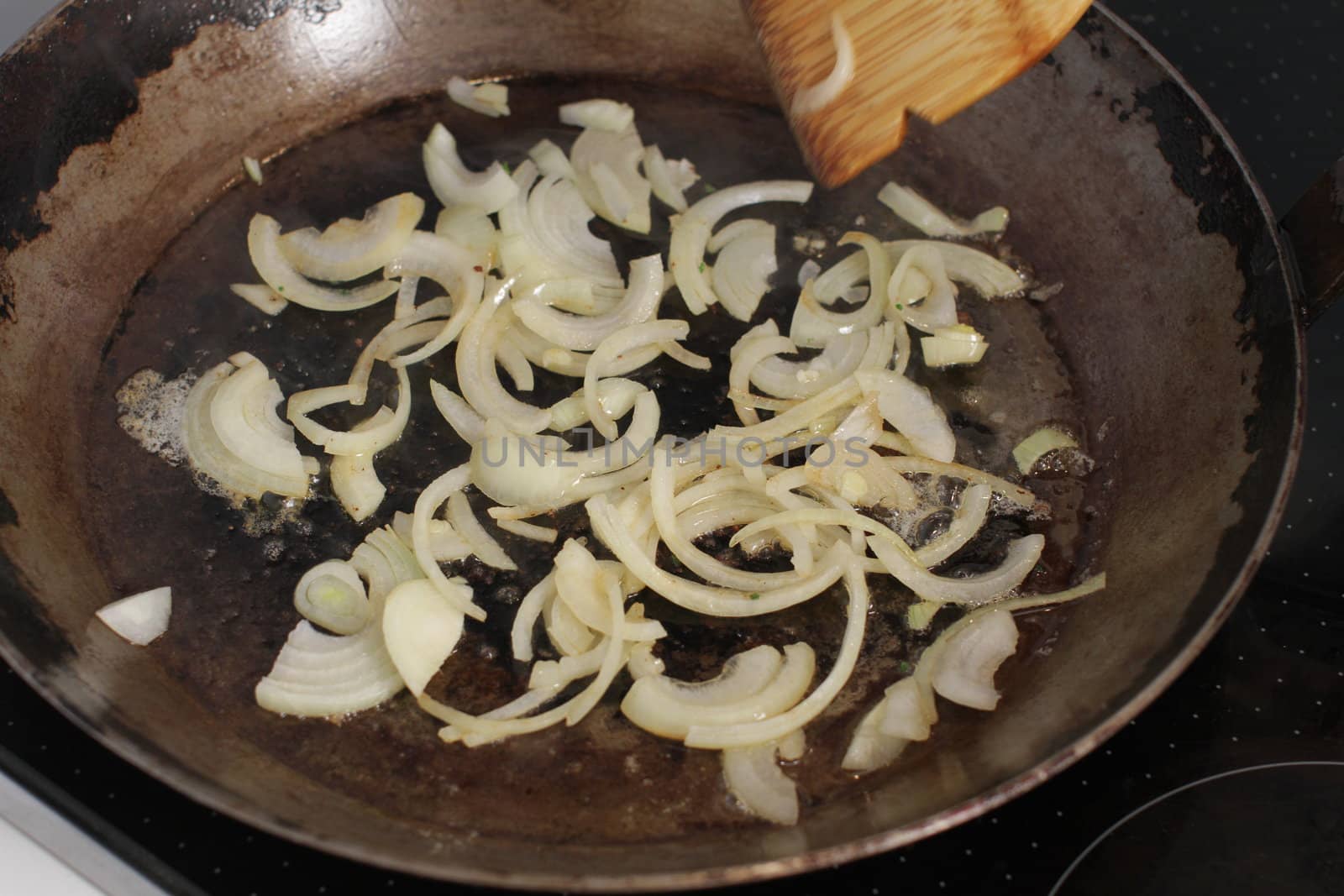 frying sliced white onions in an old pan