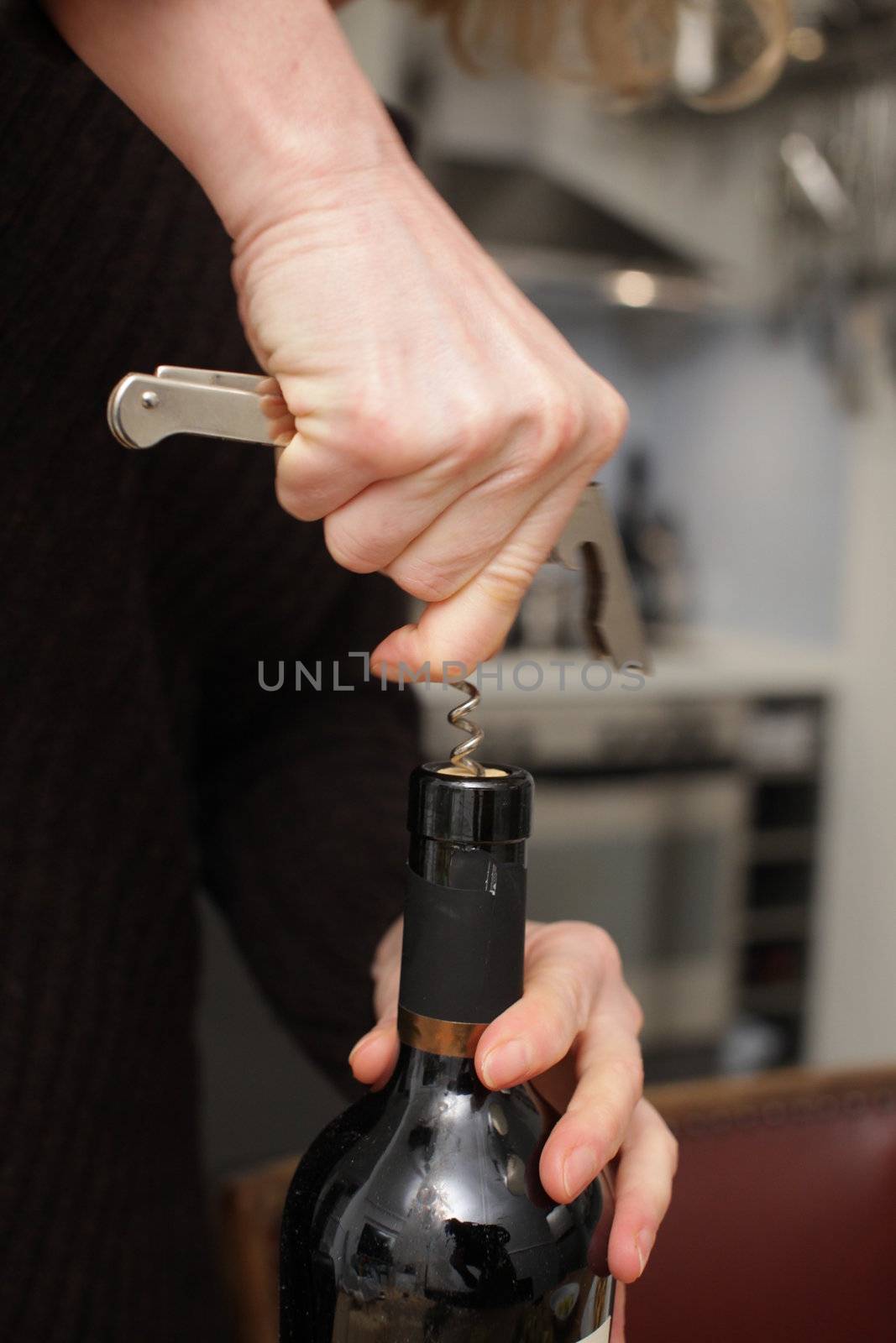 Opening a wine bottle with corkscrew in a kitchen