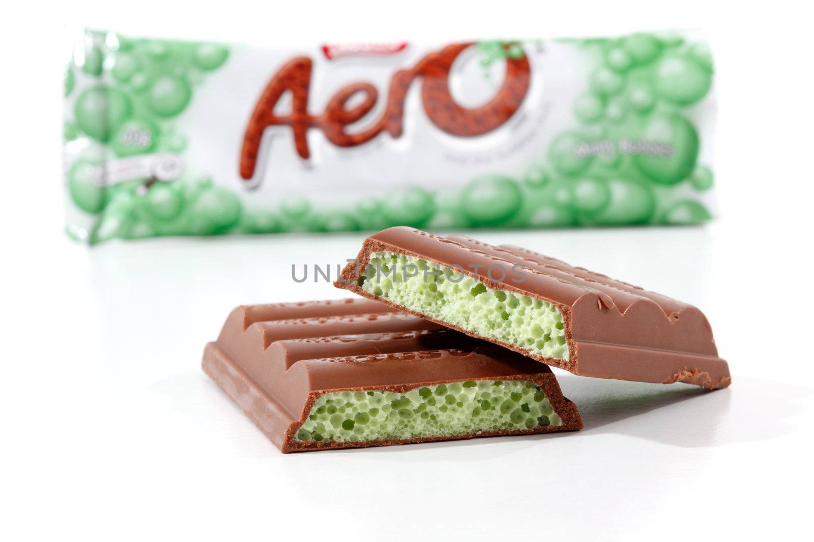 Nestle Aero chocolate bar minty bubbles 40g (453kj) .  Showing wrapper packaging in background and pieces of the chocolate bar in focus in the foreground.  Photographed in studio on a white background.