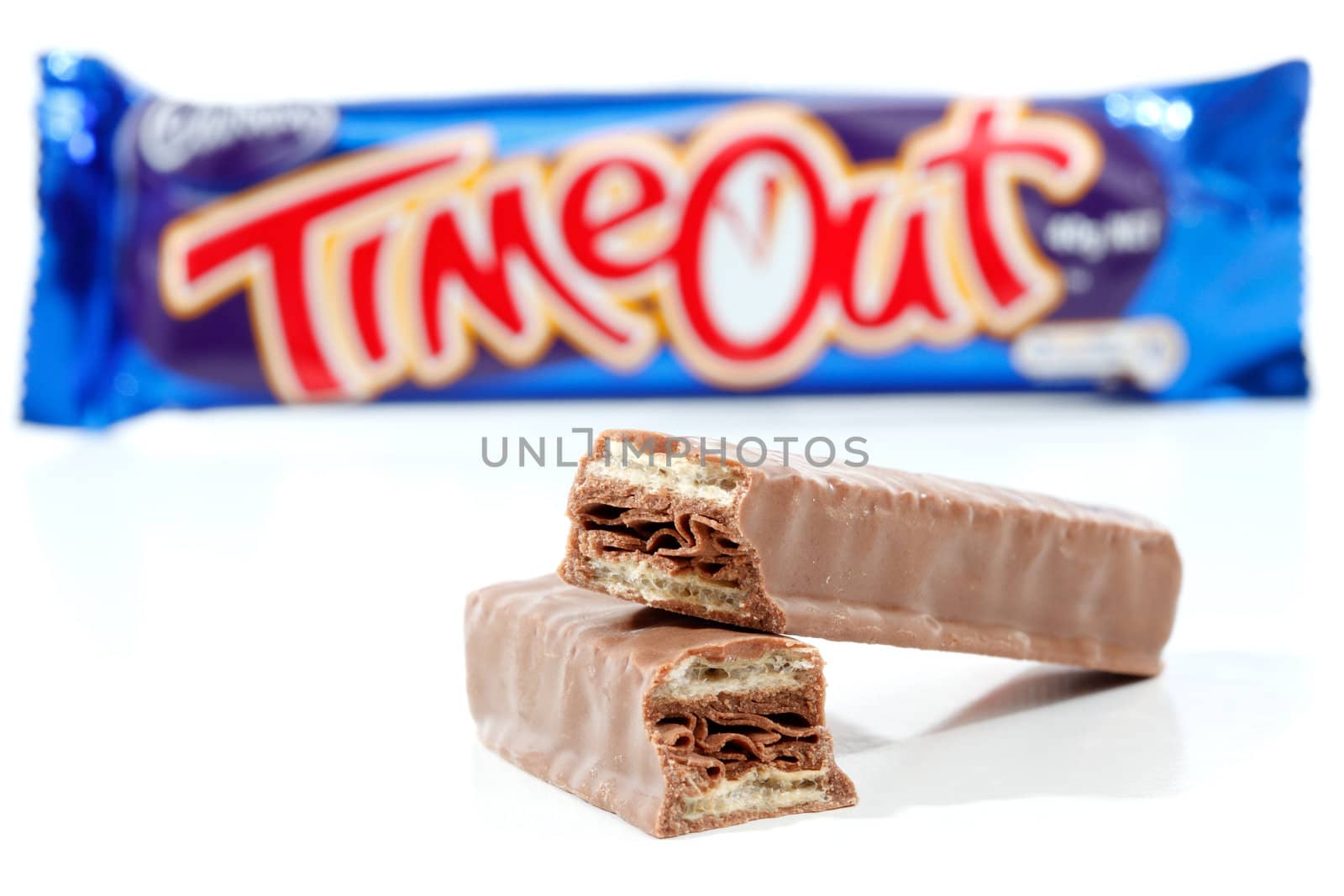 Cadbury Timout chocolate bar 40g (892kj)  Showing wrapper in background and chocolate contents in focus in the foreground.   Timeout consists of wafer biscuits with a flake chocolate centre and coated in milk chocolate.  Photographed in studio on a white background.