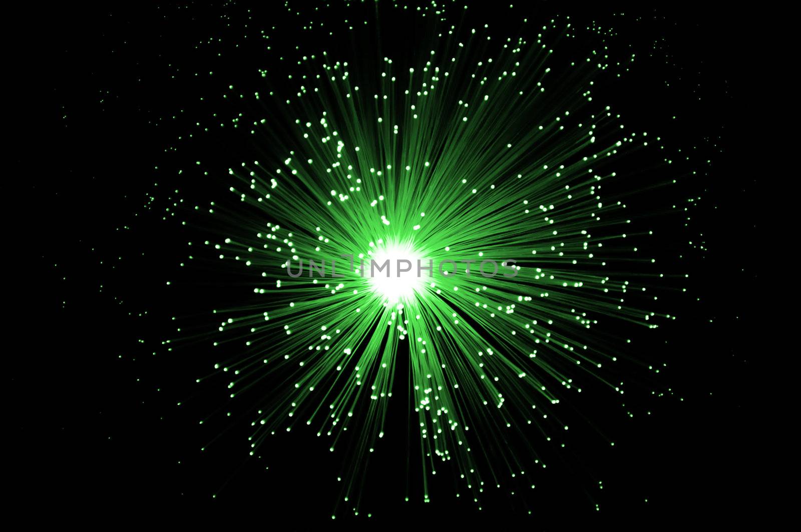 Overhead of illuminated green fiber optic light strands against black background