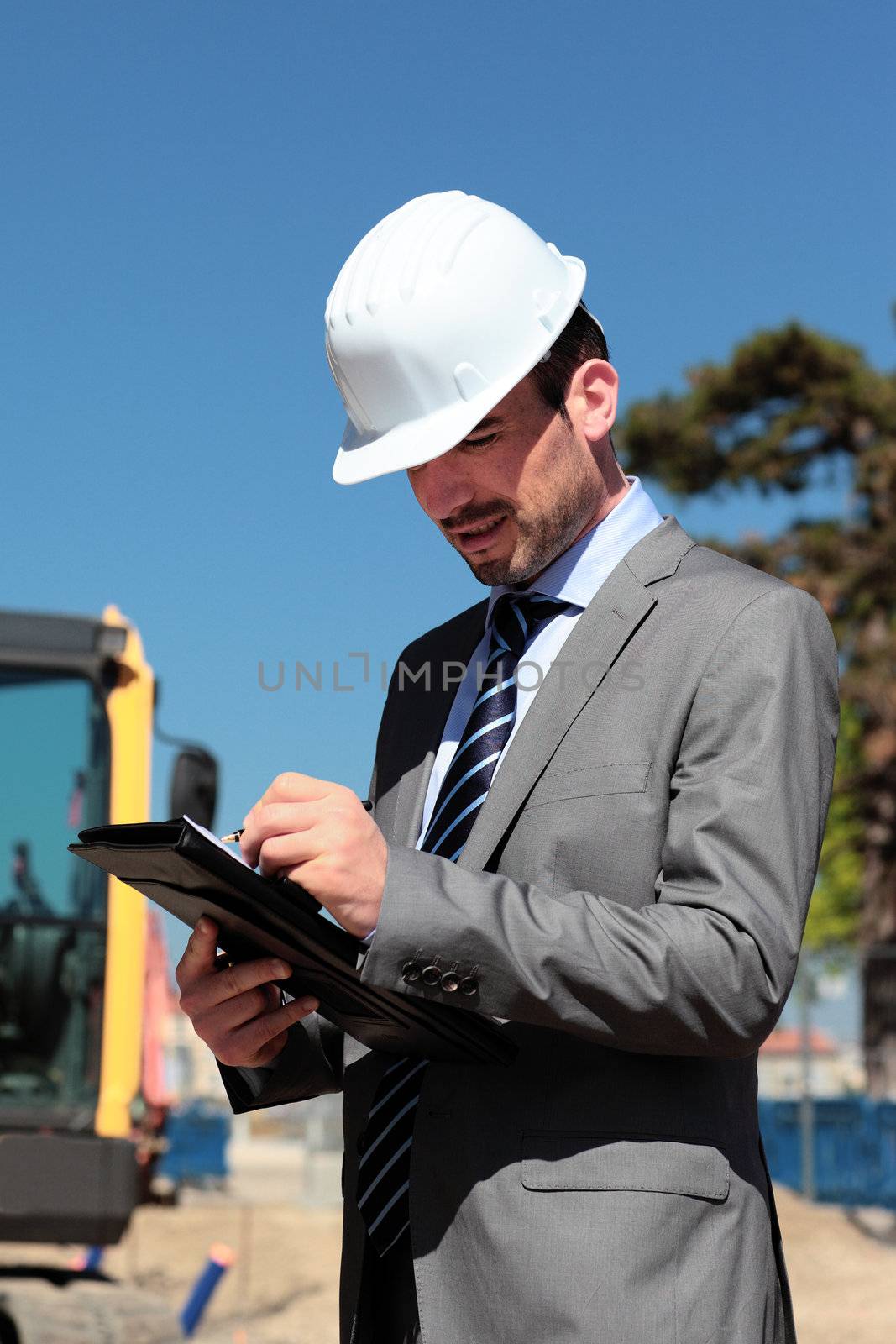 young man with hardhat and pen on building site