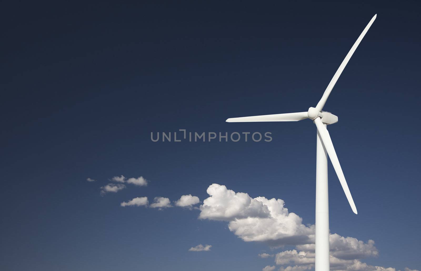 Single Wind Turbine Over Dramatic Blue Sky and Clouds.