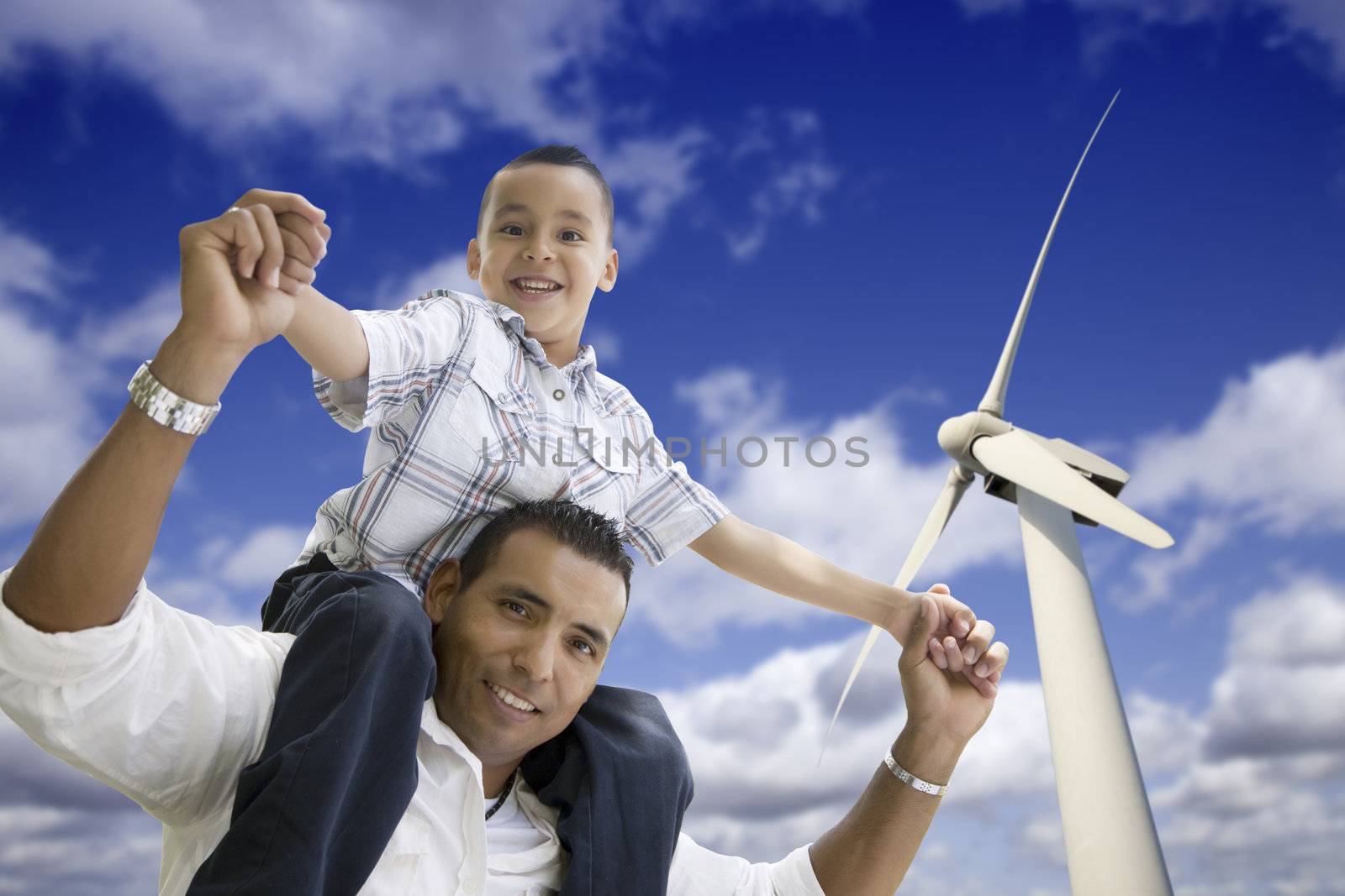 Happy Hispanic Father and Son with Wind Turbine Over Blue Sky.