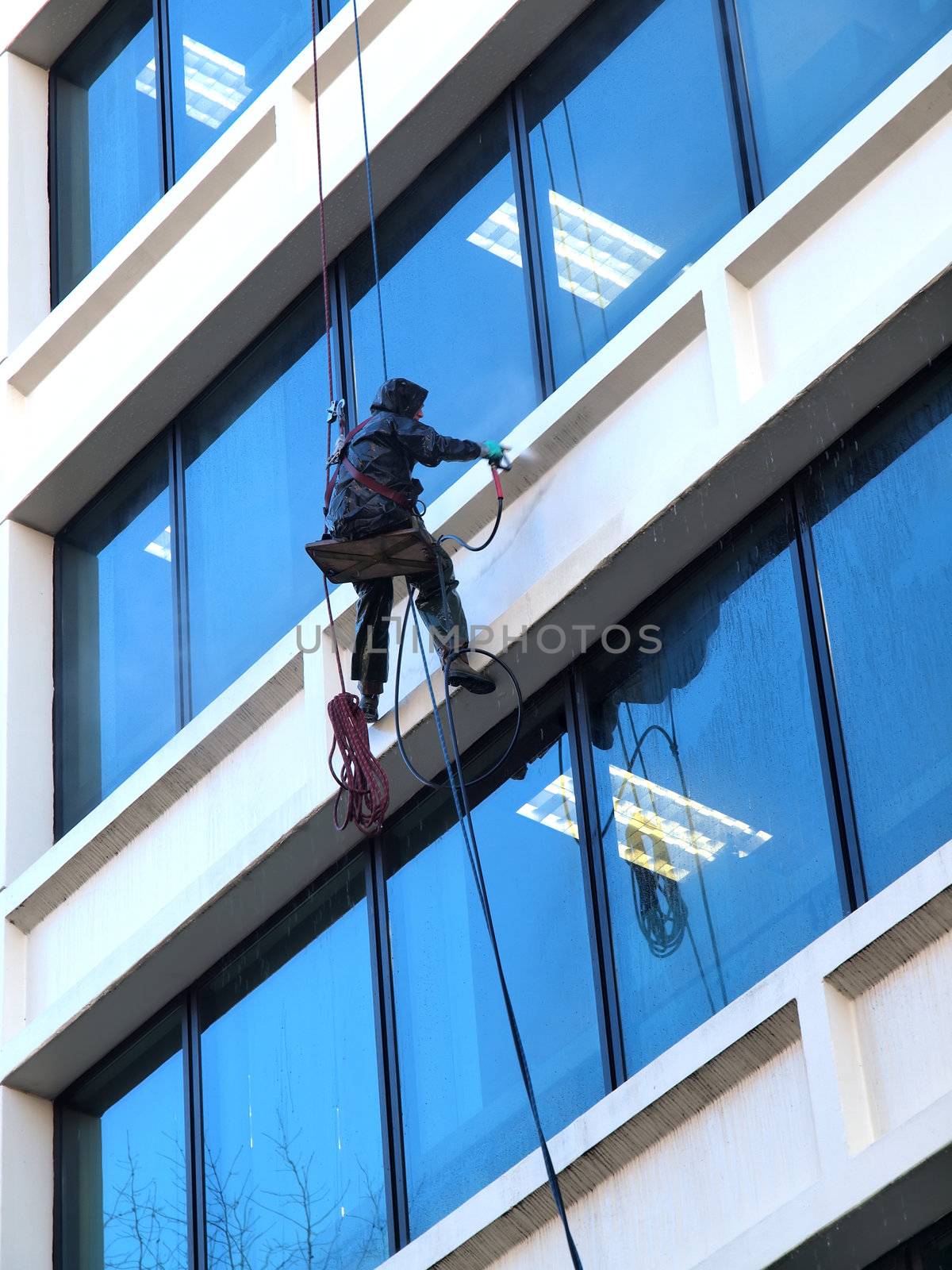 A man hanging by the ropes pressure washing an office building in downtown Portland OR.