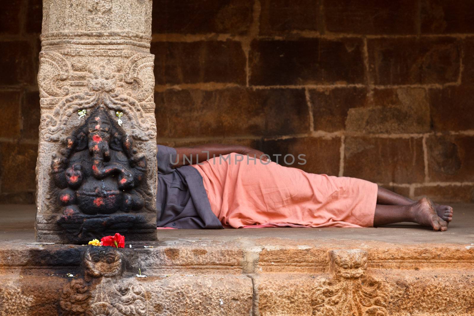 Man sleeping behing the column with Ganesha images. in Hindu temple. Sri Ranganathaswamy Temple. Tiruchirappalli (Trichy), Tamil Nadu, India
