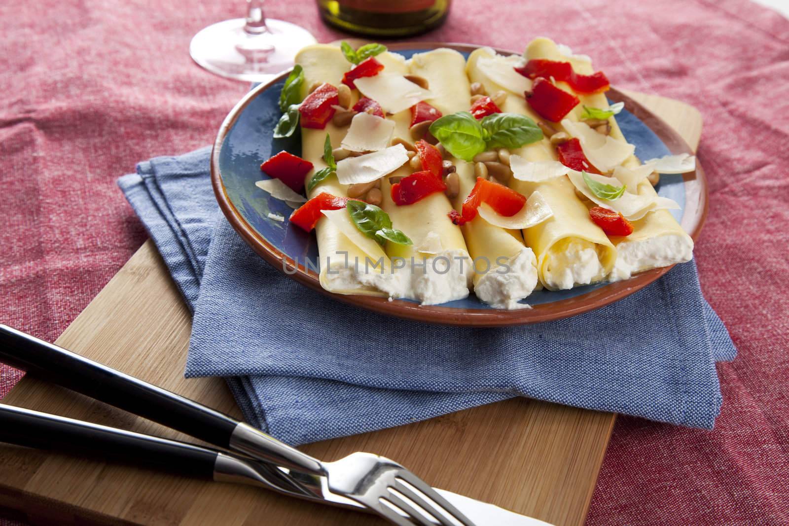 Ricotta stuffed cannelloni topped with red peppers, basil and Parmesan cheese flakes.
