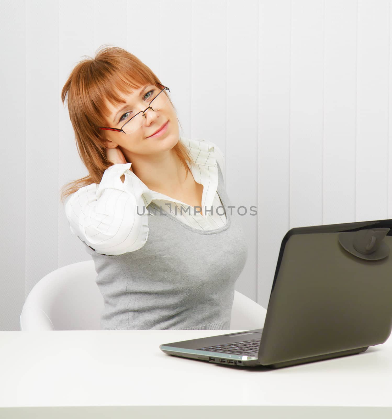 tired girl with a laptop stretches in the workplace