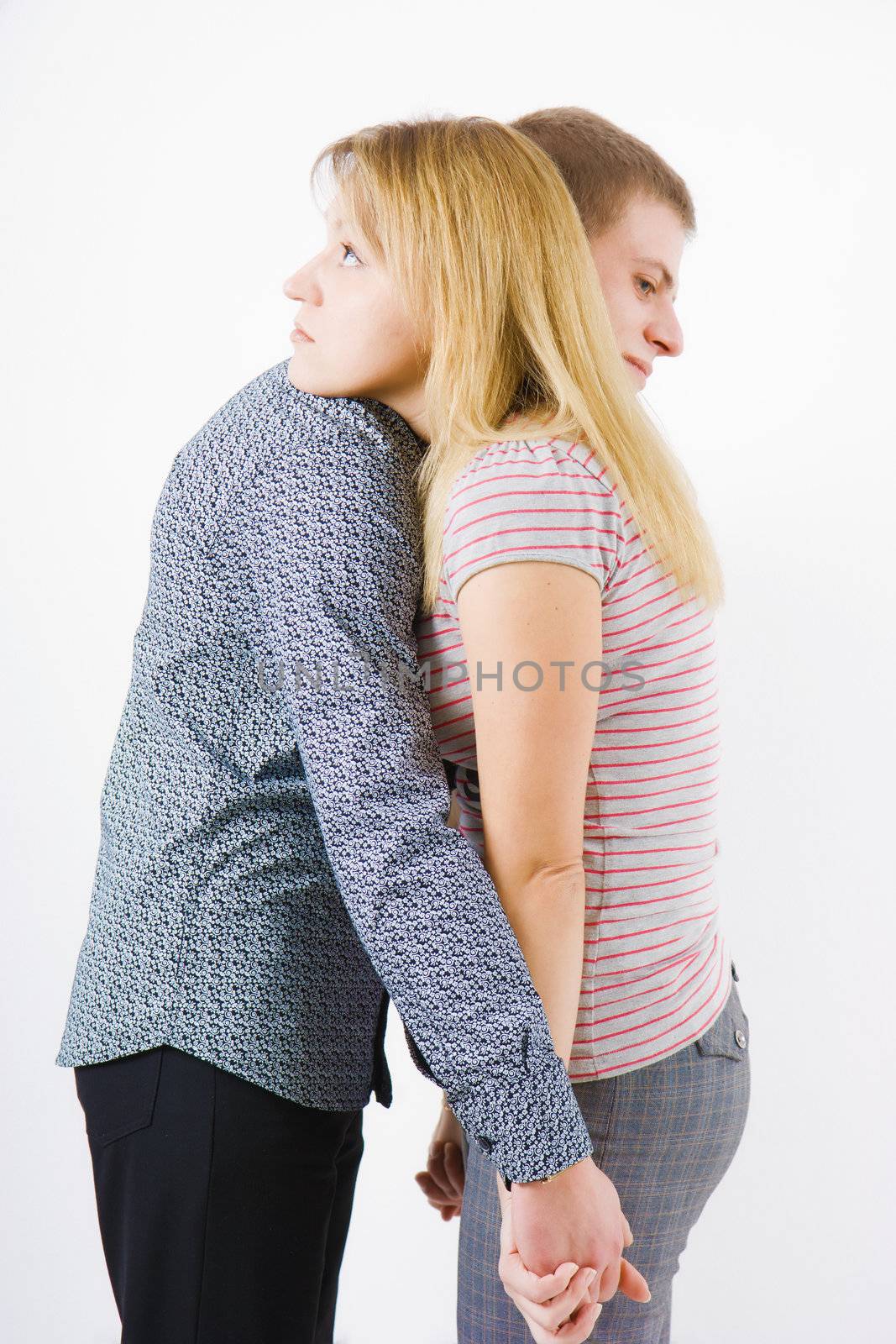 A young couple embraces on a white background
