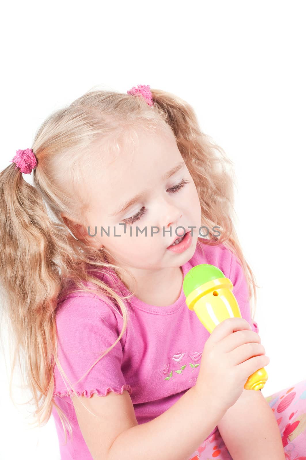 Little cute girl in pink and with ponytails in studio