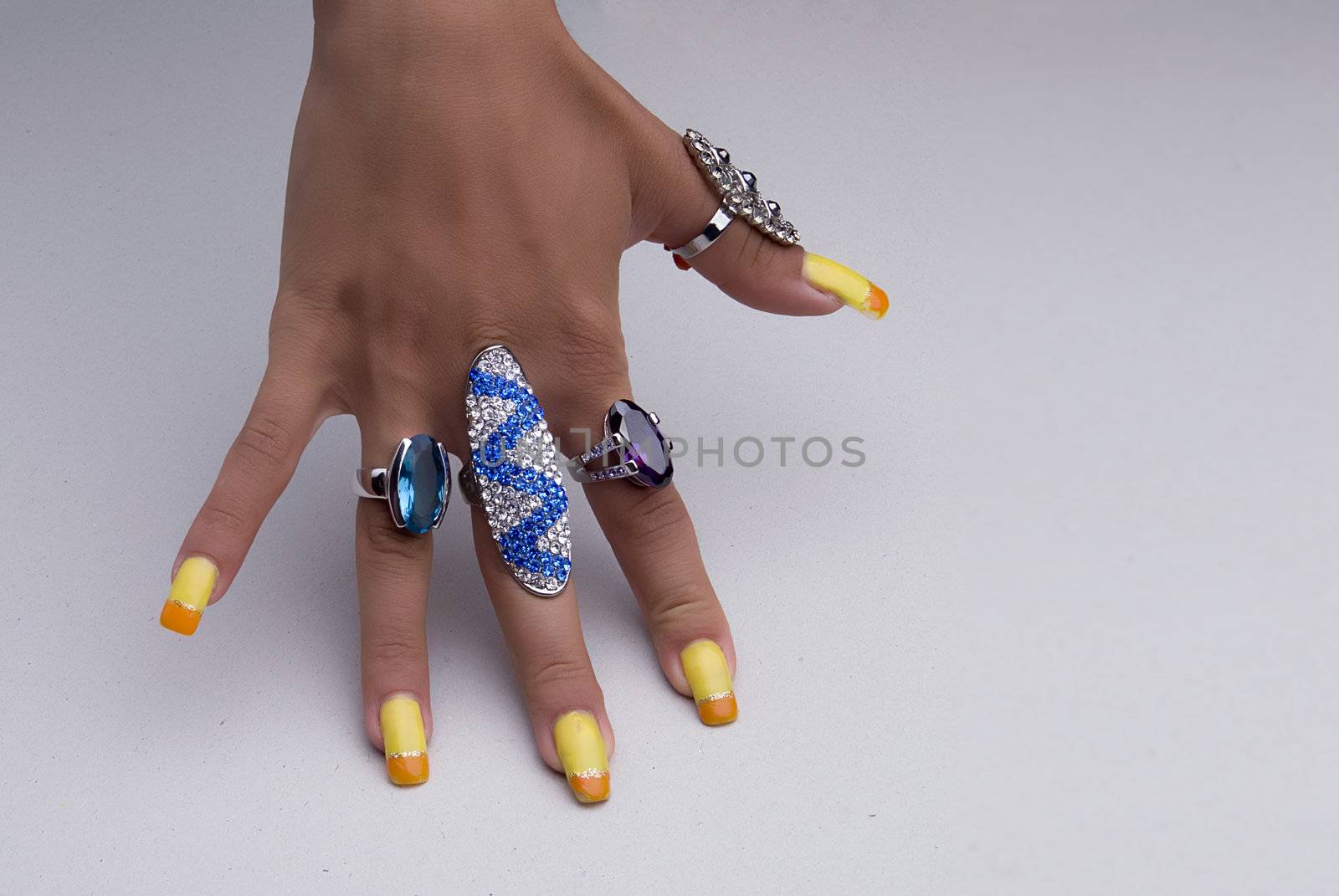 Hand showing big rings on fingers, colored nails