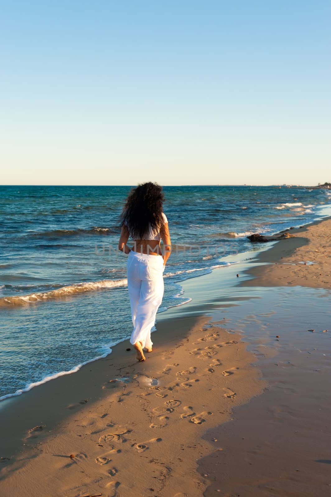 Hispanic woman enjoying beach walk on a mild sunny afternoon