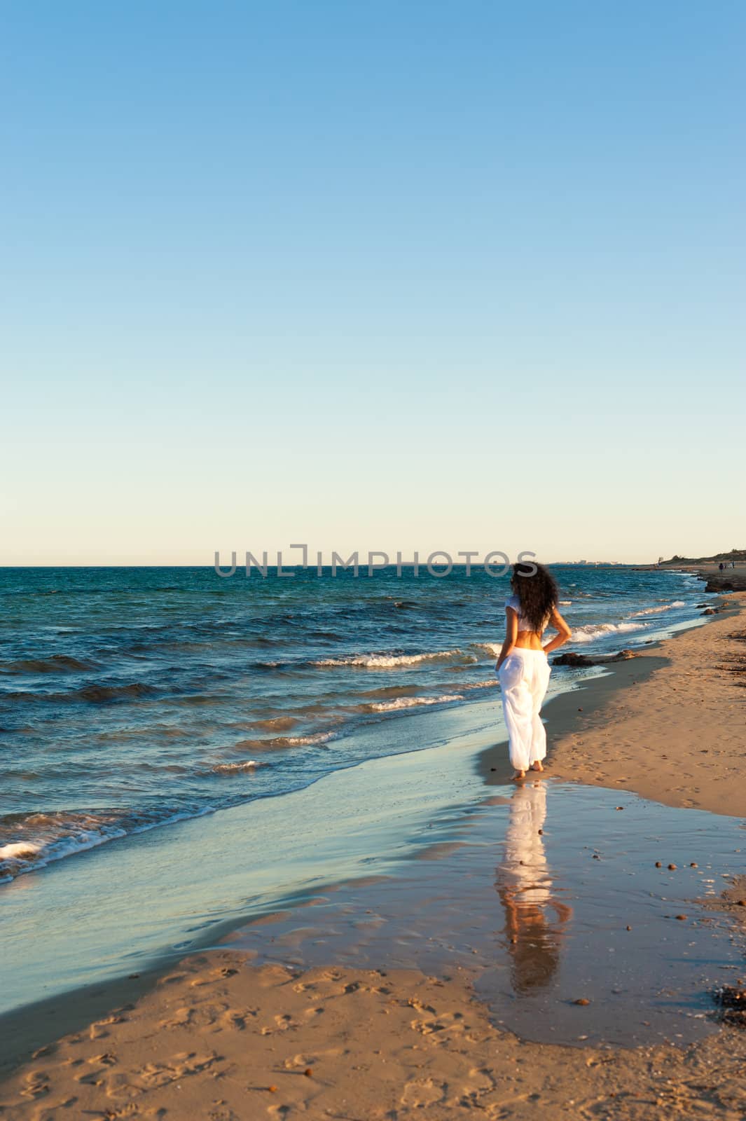 Hispanic woman enjoying beach walk on a mild sunny afternoon