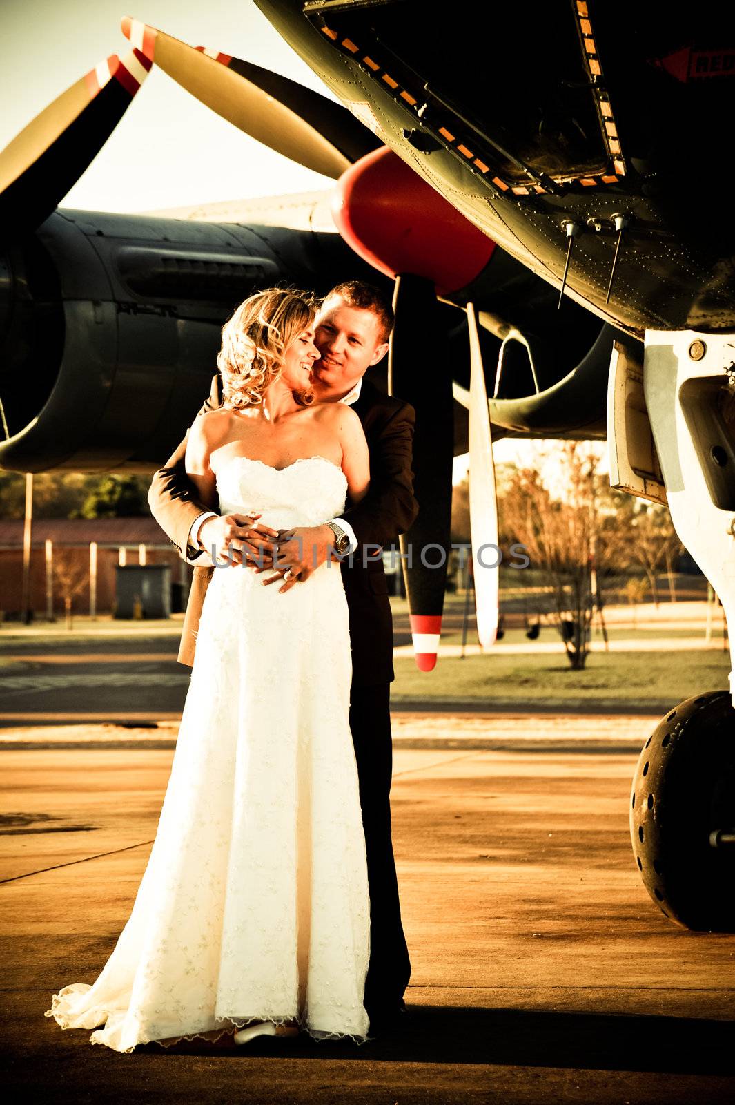 sexy young adult wedding couple standing with old war aircraft by Ansunette