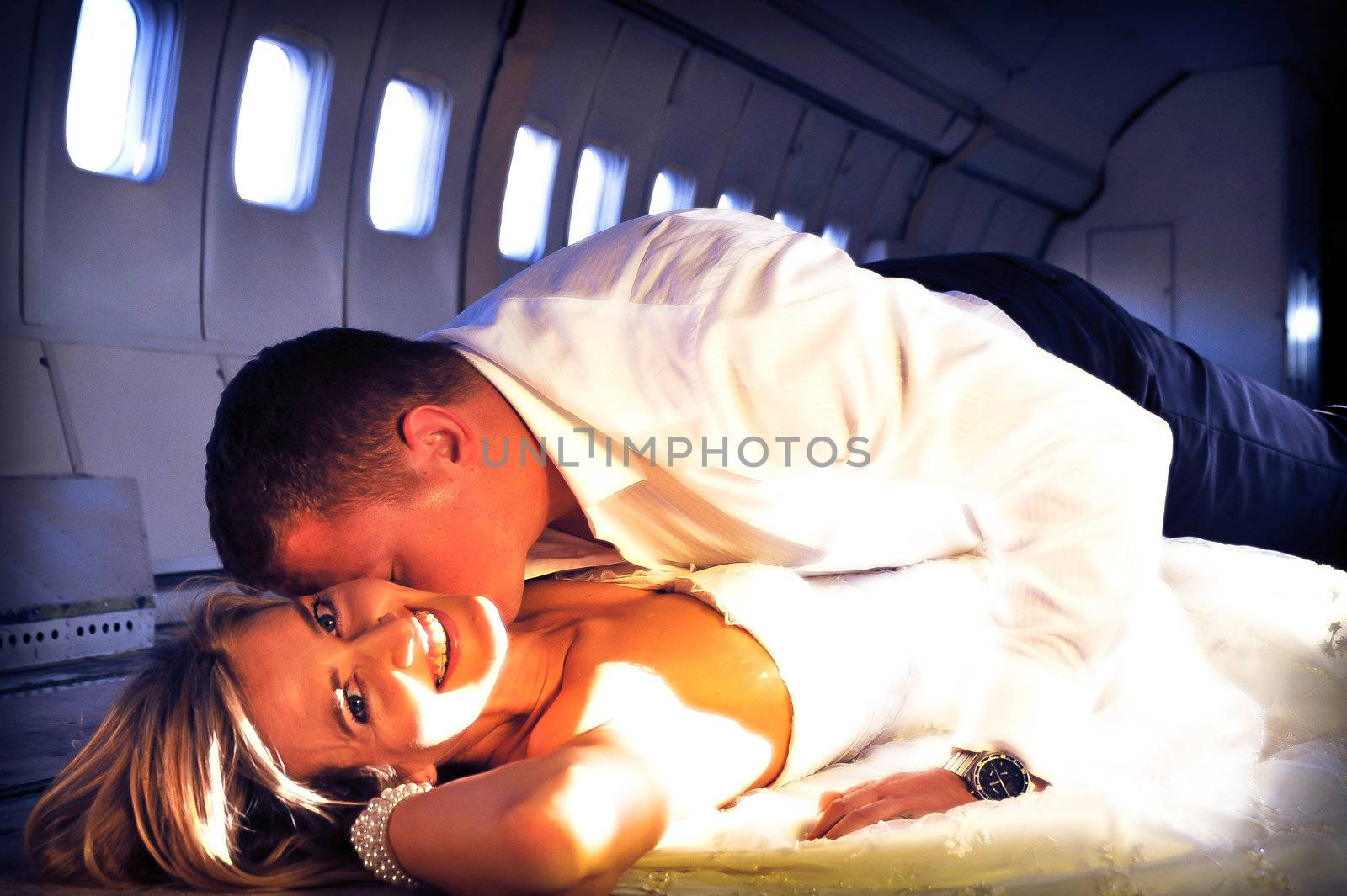 sexy young  adult wedding couple laying in the fuselage of airplane by Ansunette