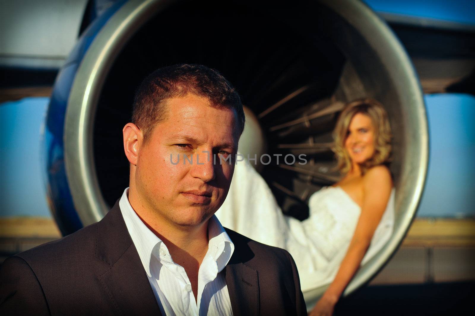 sexy young adult wedding couple laying inside the engine intake of Boeing passenger aircraft with groom in front