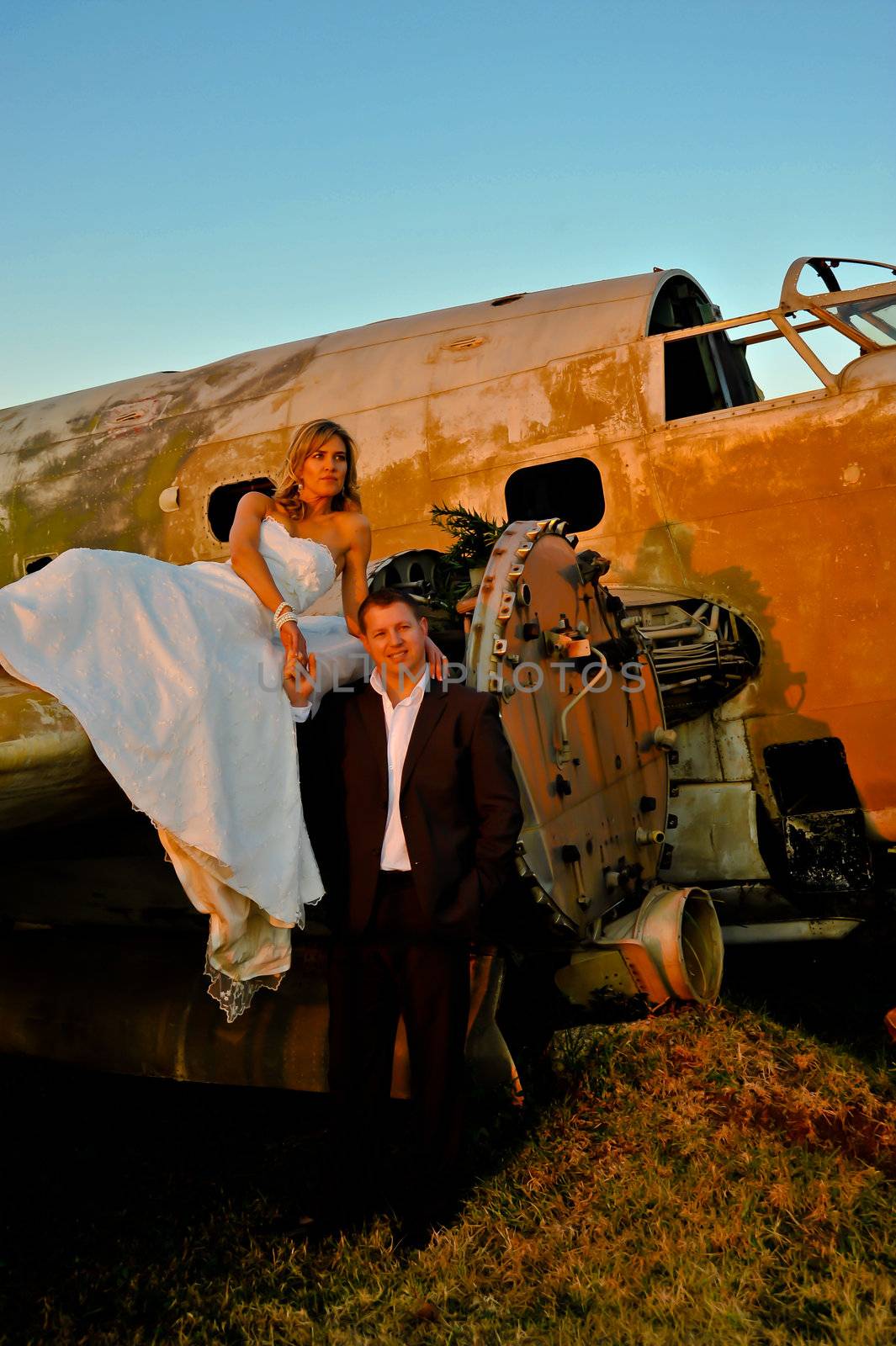 young wedding couple standing at crashed old Dakota war plane by Ansunette