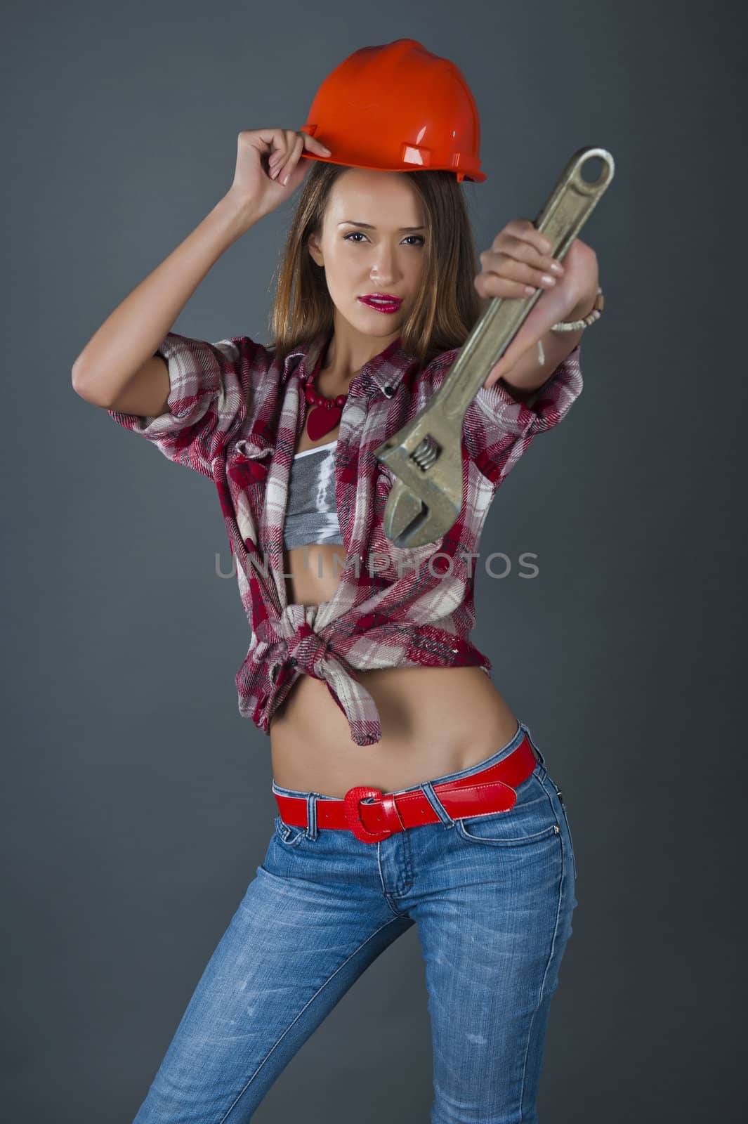 Beautiful sexual model in a building helmet and with an adjustable spanner in hands