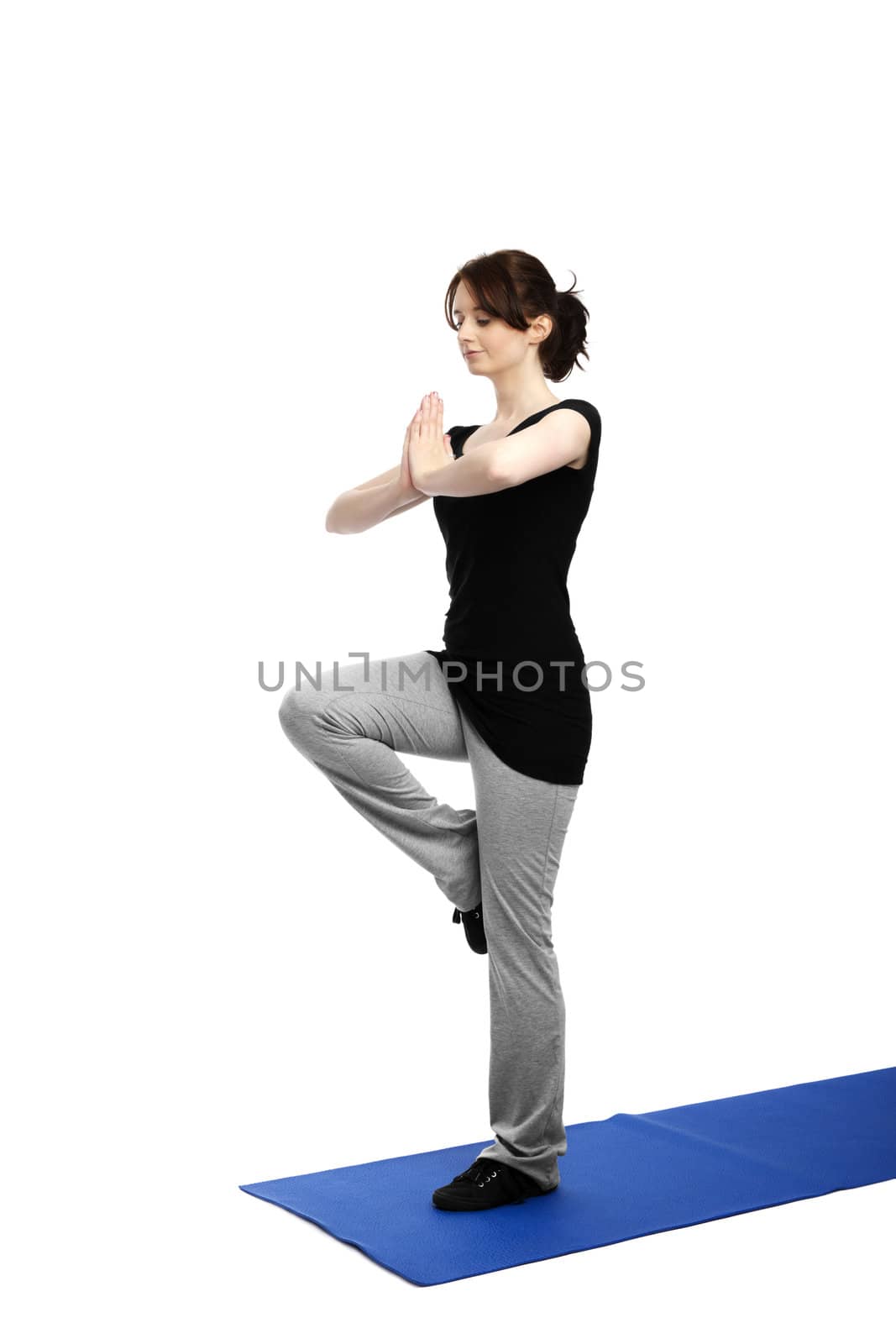young woman exercising yoga on one leg on a blue mat
