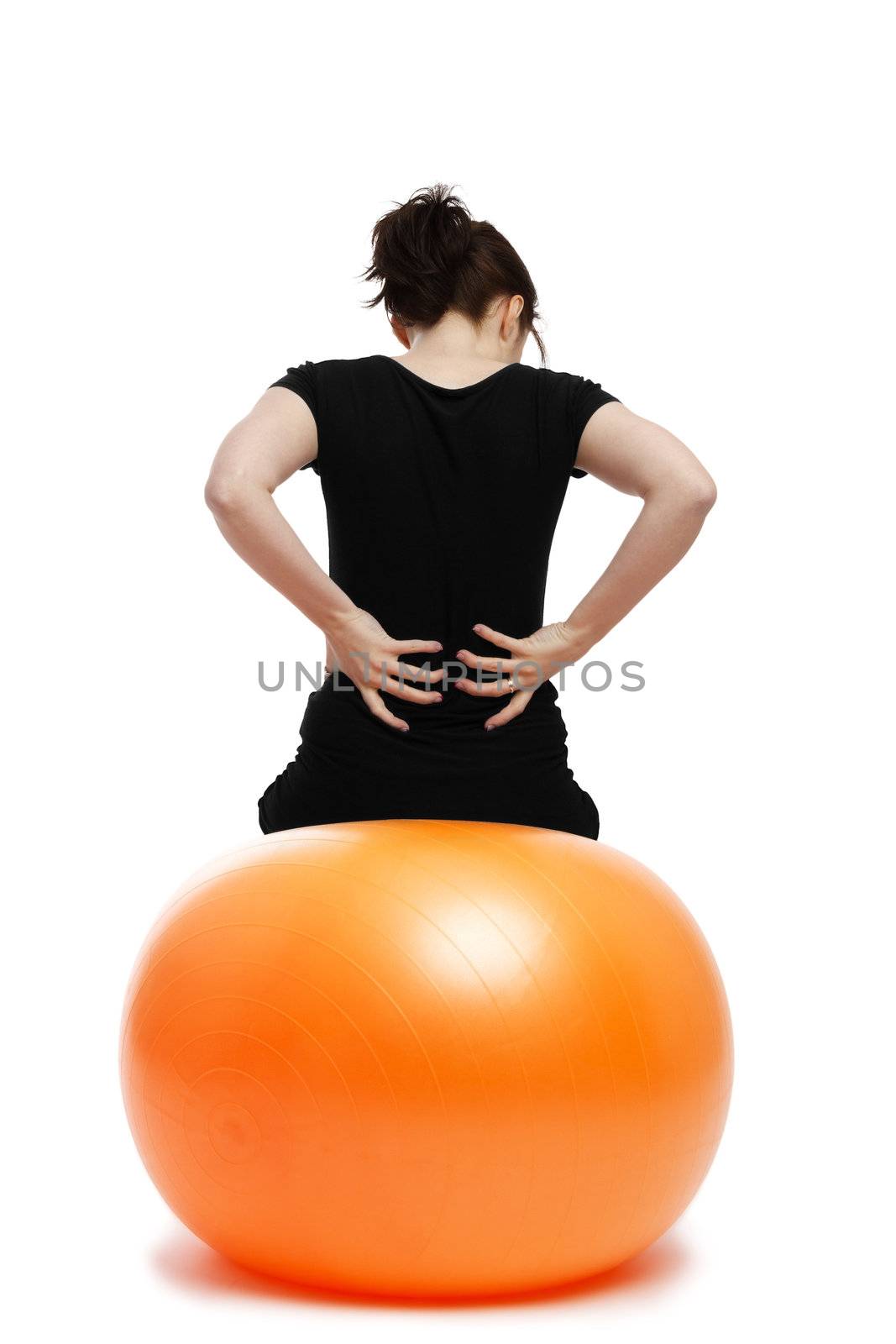 young woman with pain in the back sitting on orange exercise ball