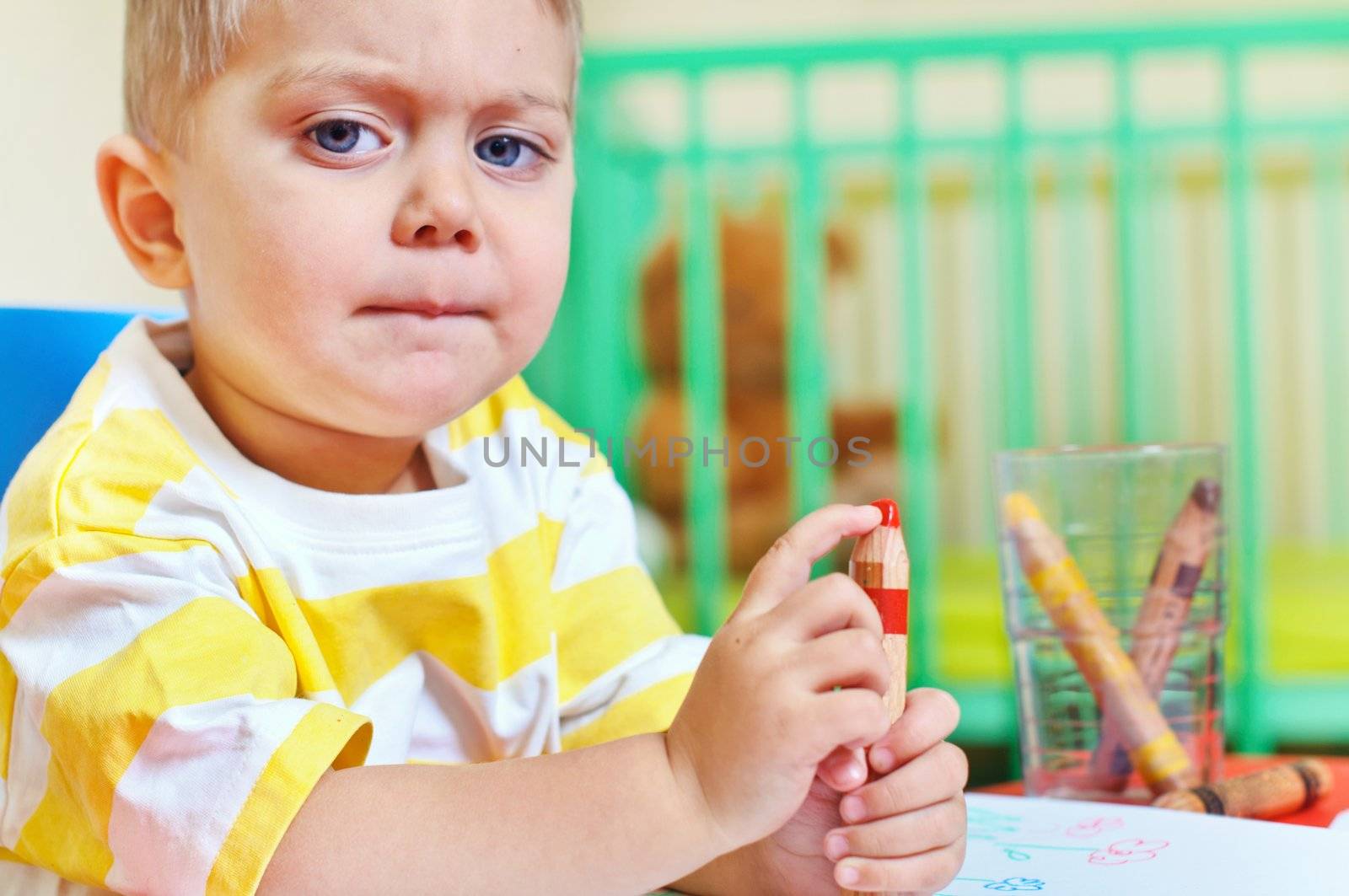 Little cute boy draws with crayons in the nursery by maxoliki