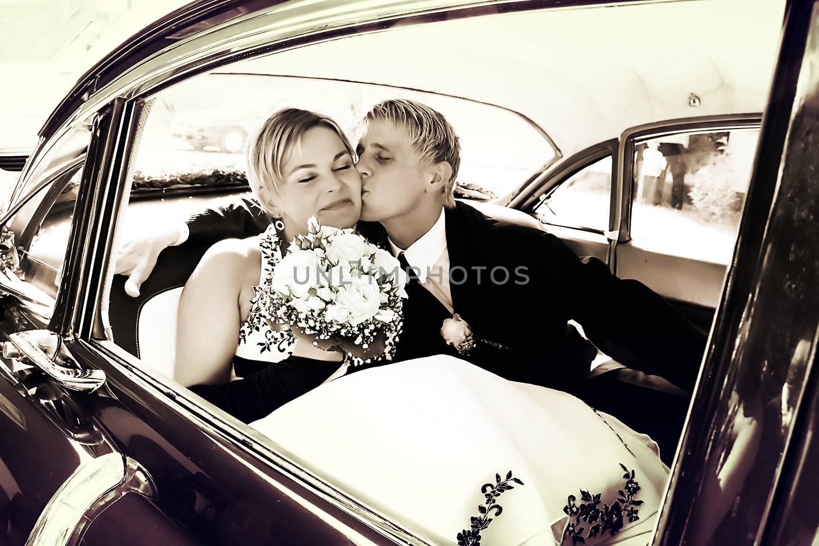 Groom kisses Bride on the backseat of a car