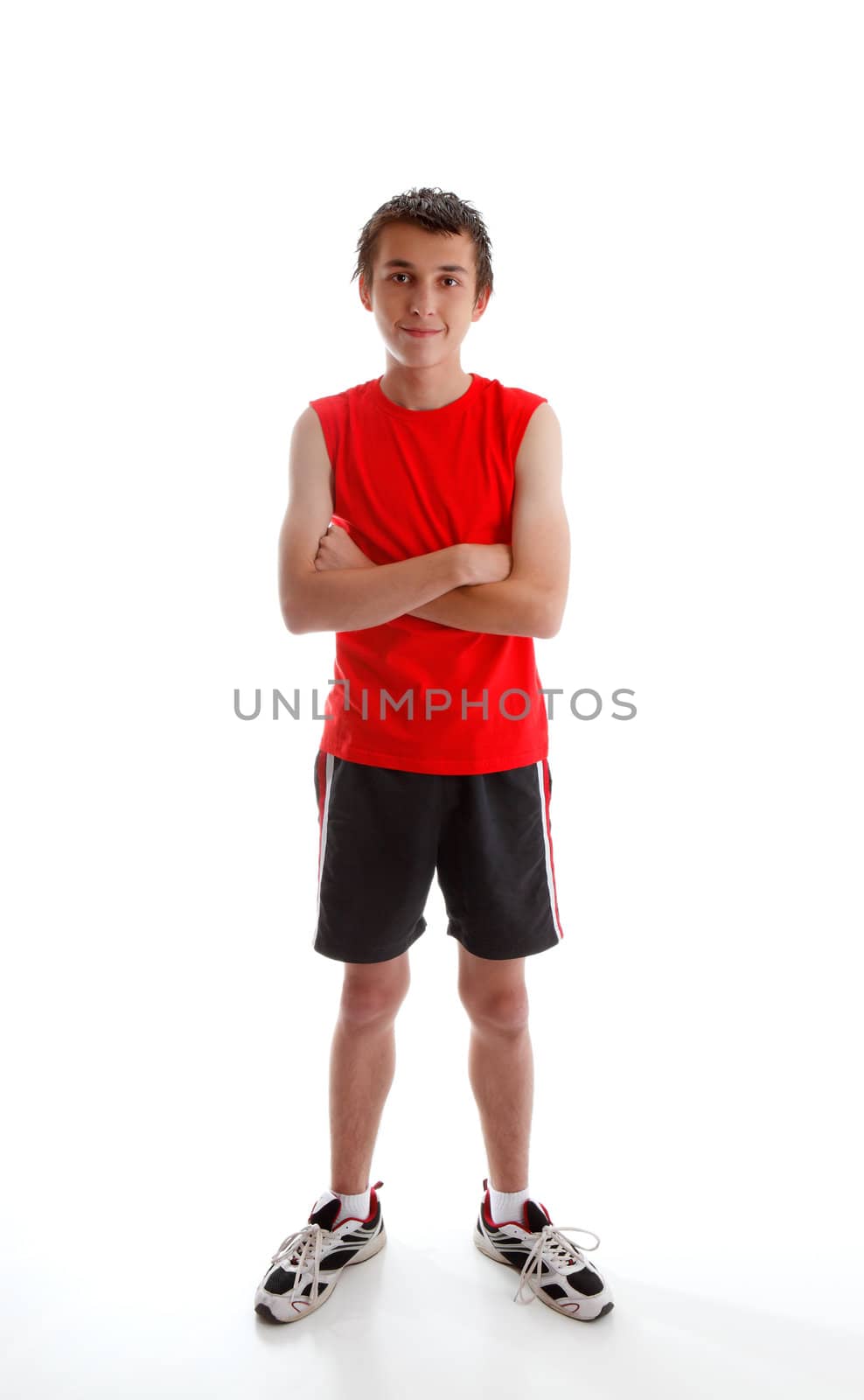 A young boy teenager wearing sports wear clothing, tank top, shorts and  sports shoes and standing with arms crossed.  White background.
