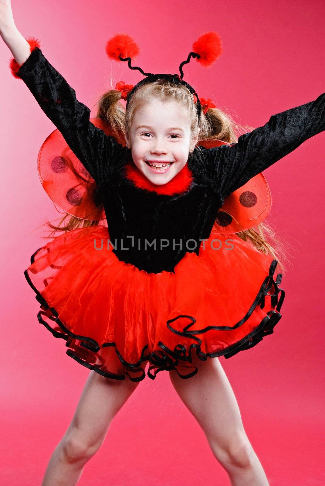 Jumping little girl dressed like a ladybug. Studio shot.