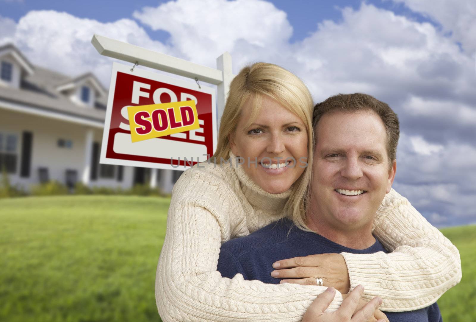 Happy Couple Hugging in Front of Sold Sign and House by Feverpitched