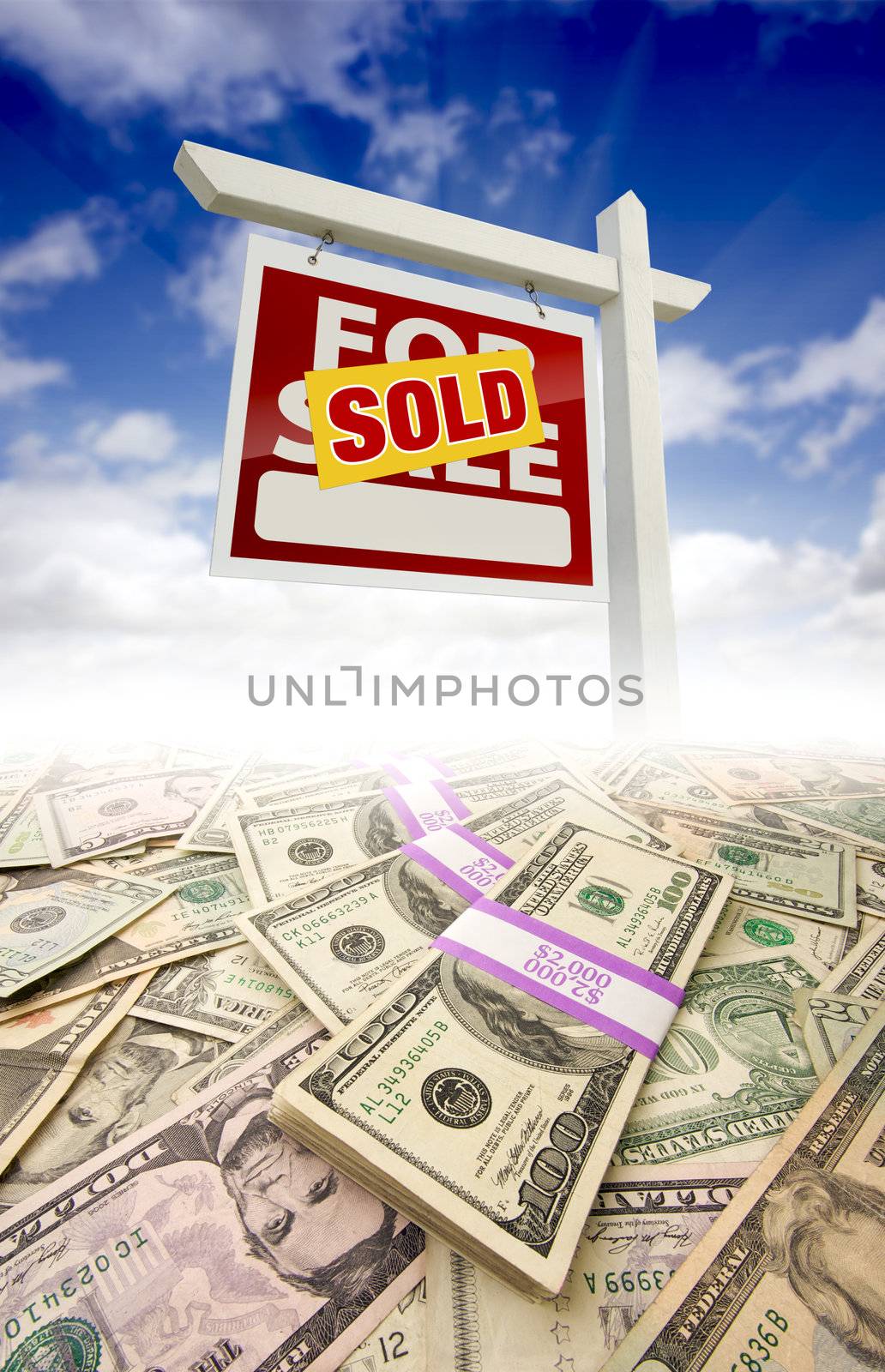 Stacks of Money Fading Off and Sold For Sale Real Estate Sign Against Blue Sky with Clouds.