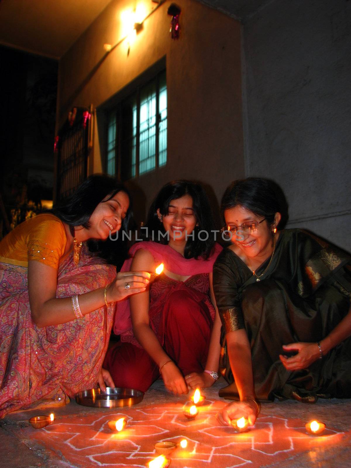Indian women from a hindu family in traditional attire arranging lamps as per culture, on the occassion of Diwali festival in India.