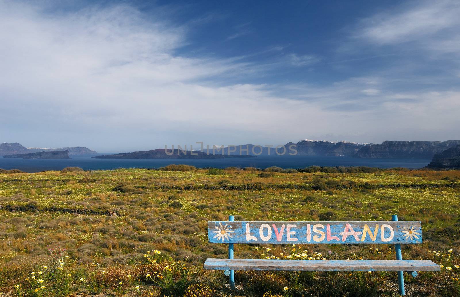 Spring setting on the island of Santorini with a bench bearing the text “Love Island”