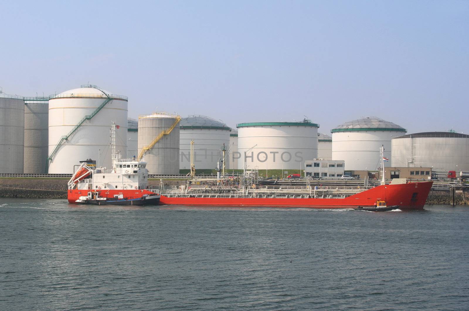 Red oil tanker among oil storage tanks in Rotterdam harbor