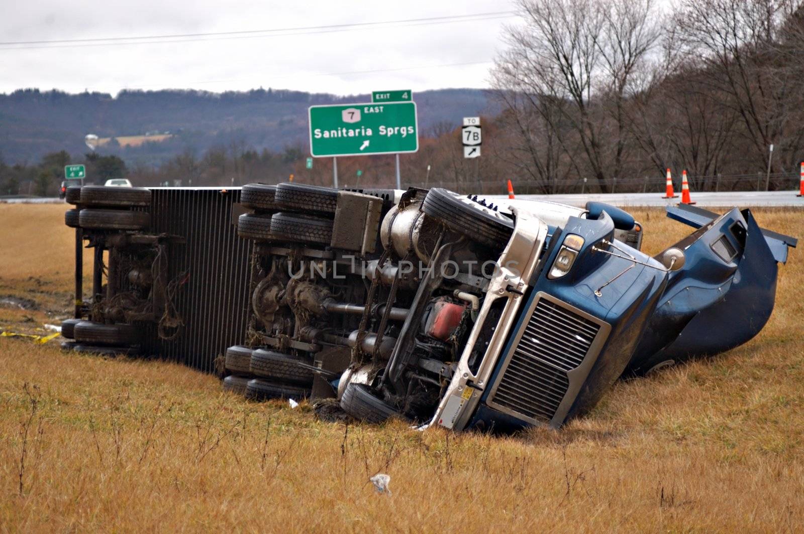 A tractor trailer on its side in the median after a roll over accident. 