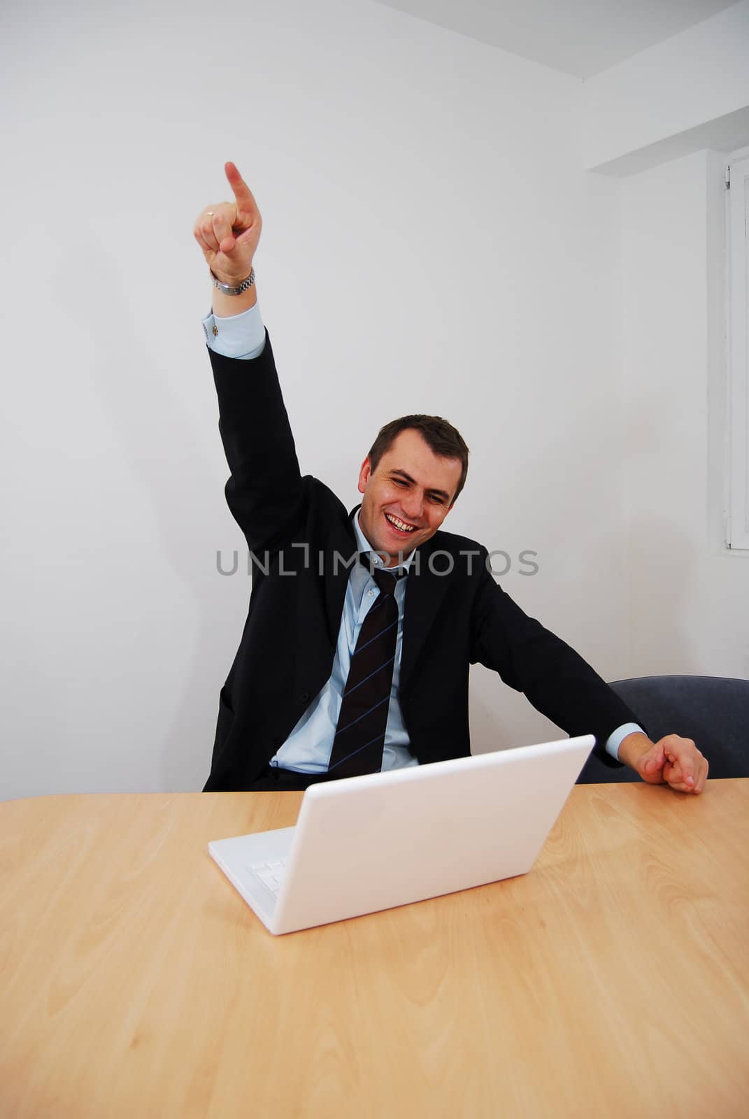 Successful businessman sitting on a table with lap-top