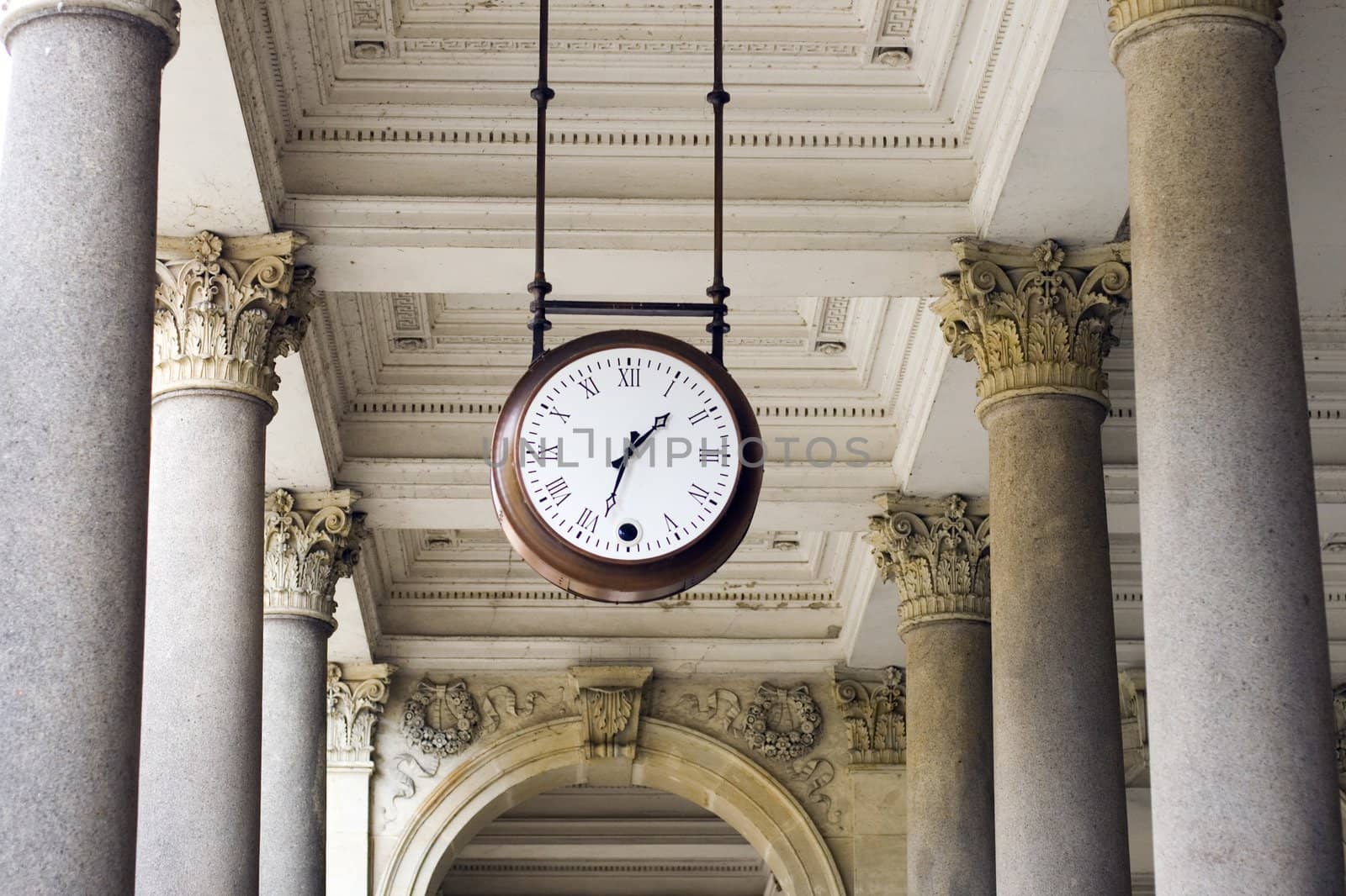 a clock hanging among pillars in the spa colonnade