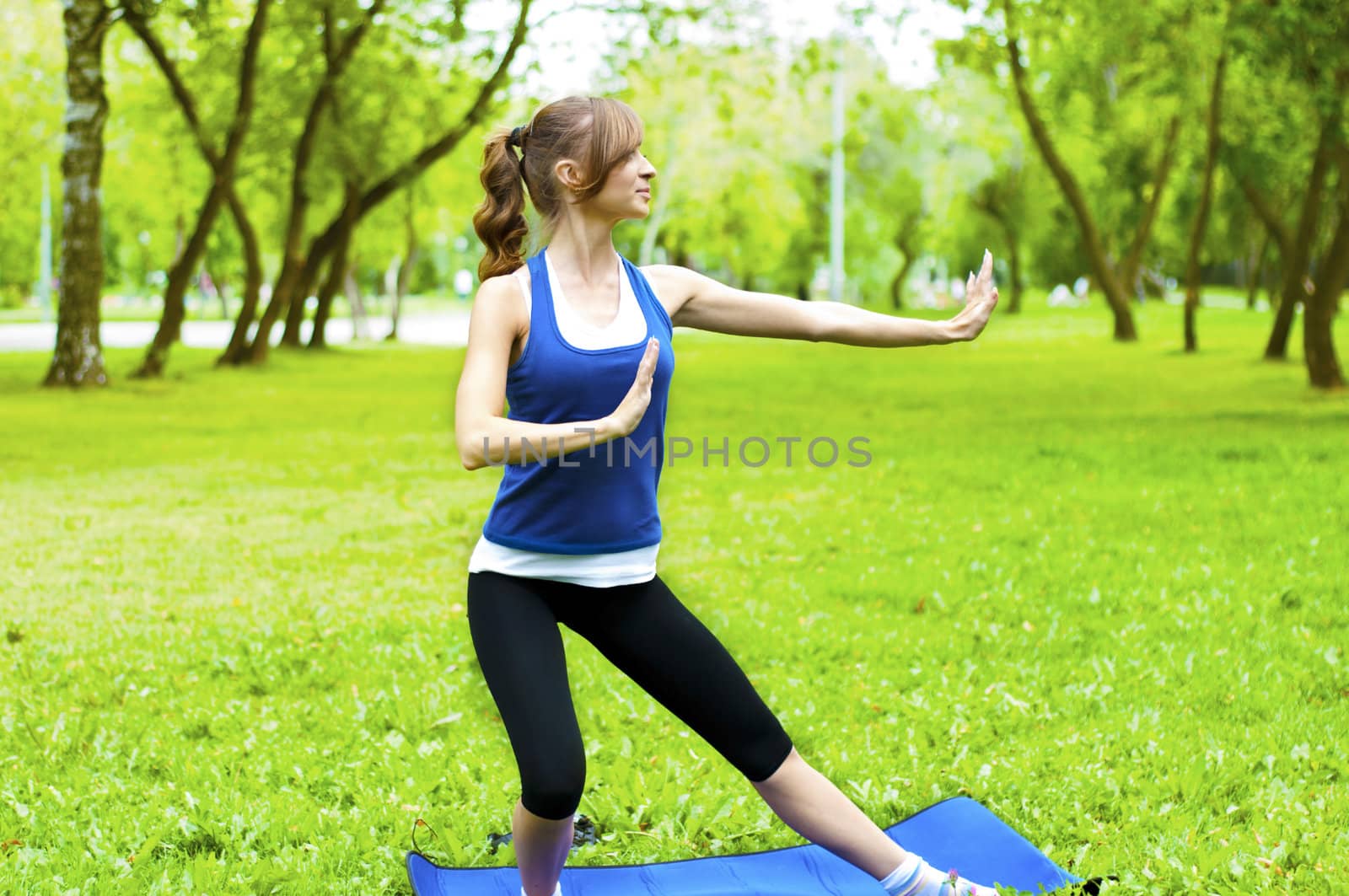 young woman is engaged in yoga, in summer forest on a green grass