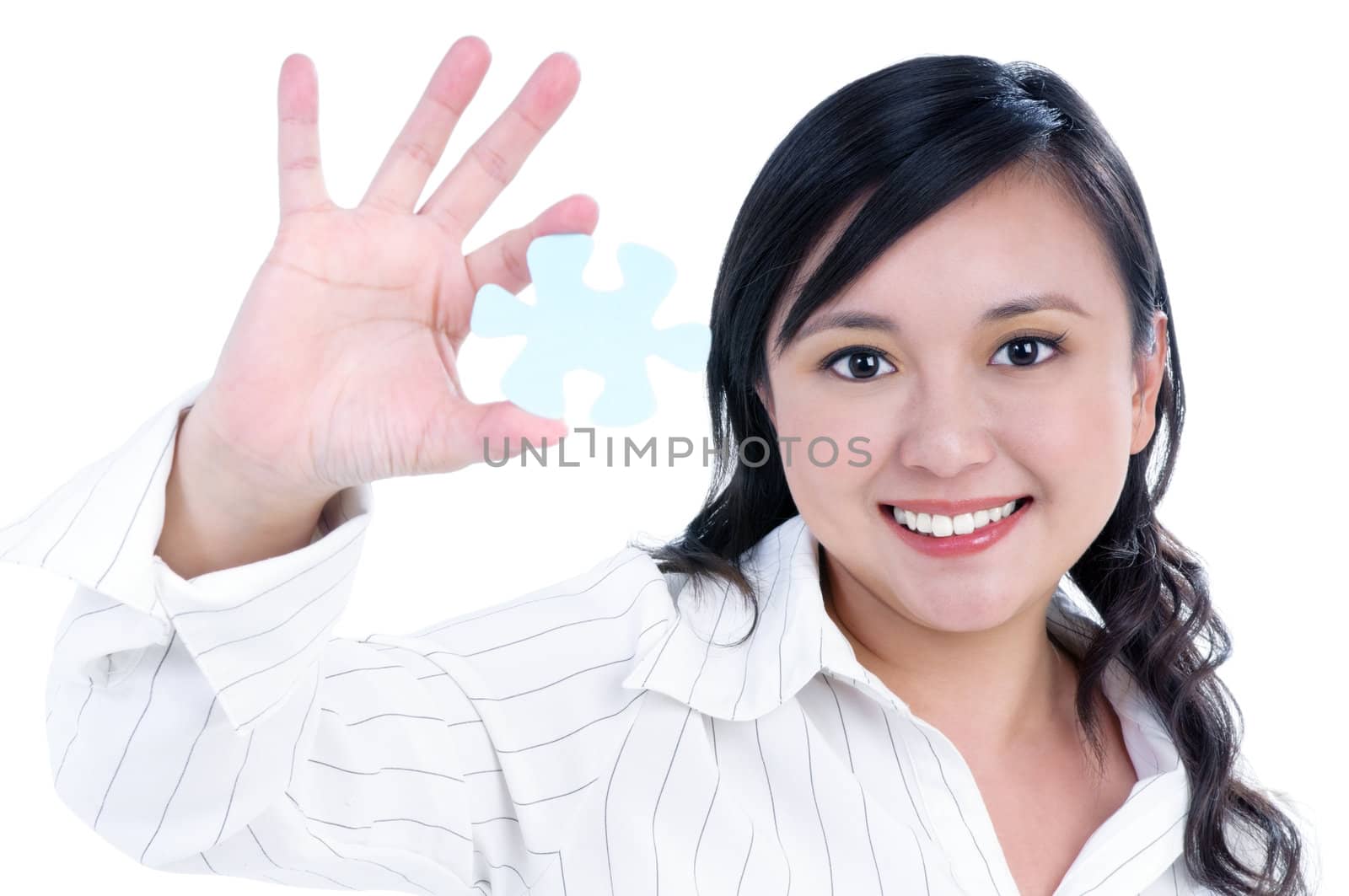 Portrait of an attractive businesswoman holding a piece of jigsaw puzzle over white background.