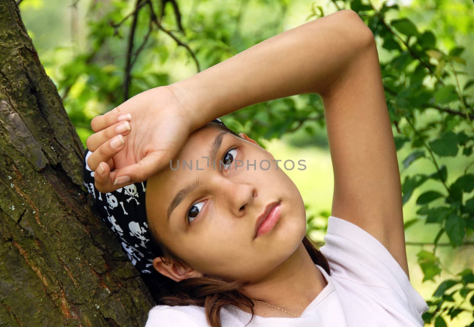 portrait of sad teenage girl outdoors by tree in black fancy kerchief