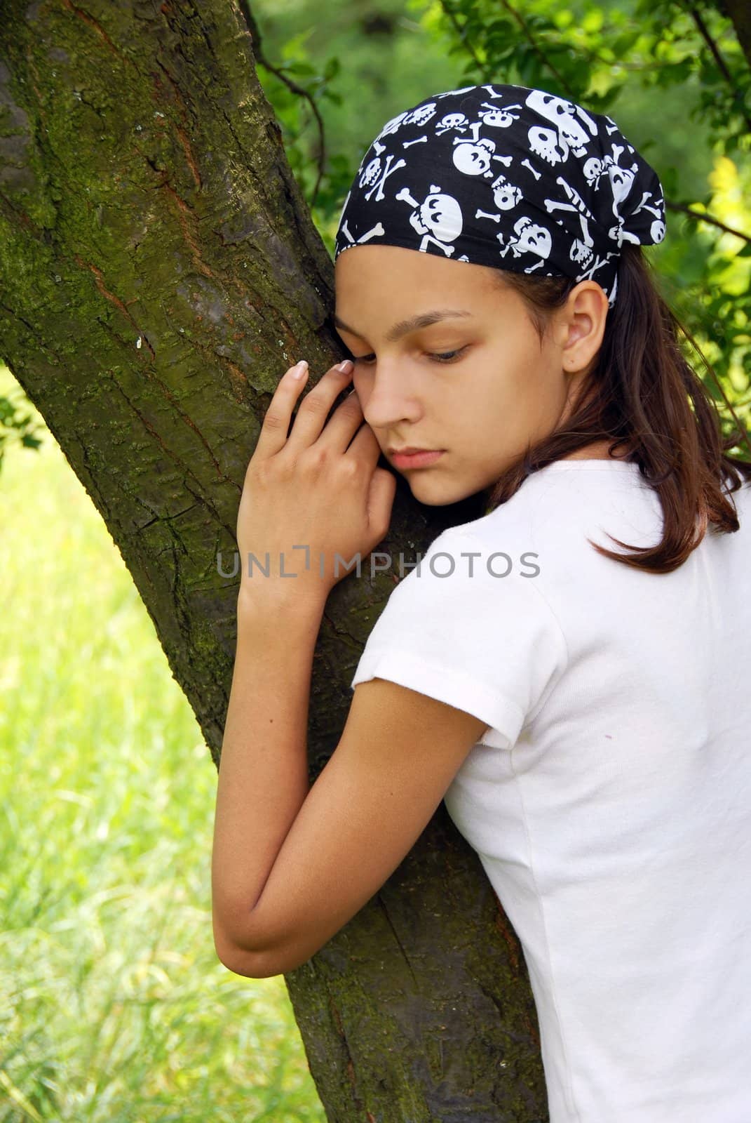 portrait of sad teenage girl outdoors by tree in black fancy kerchief