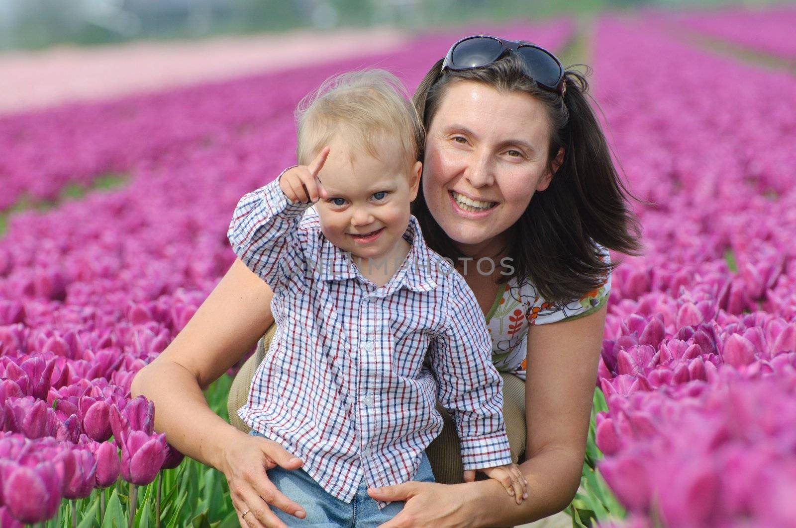 In Tulip Field. Mother with son in tulips field by maxoliki