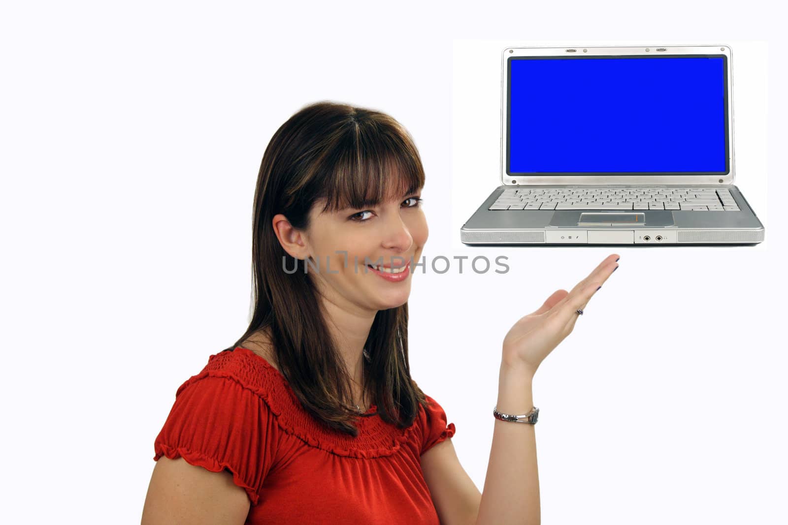 A lovely young brunette hostess with a captivating smile, looks directly at the viewer while pointing to a laptop computer which displays a blank blue screen.