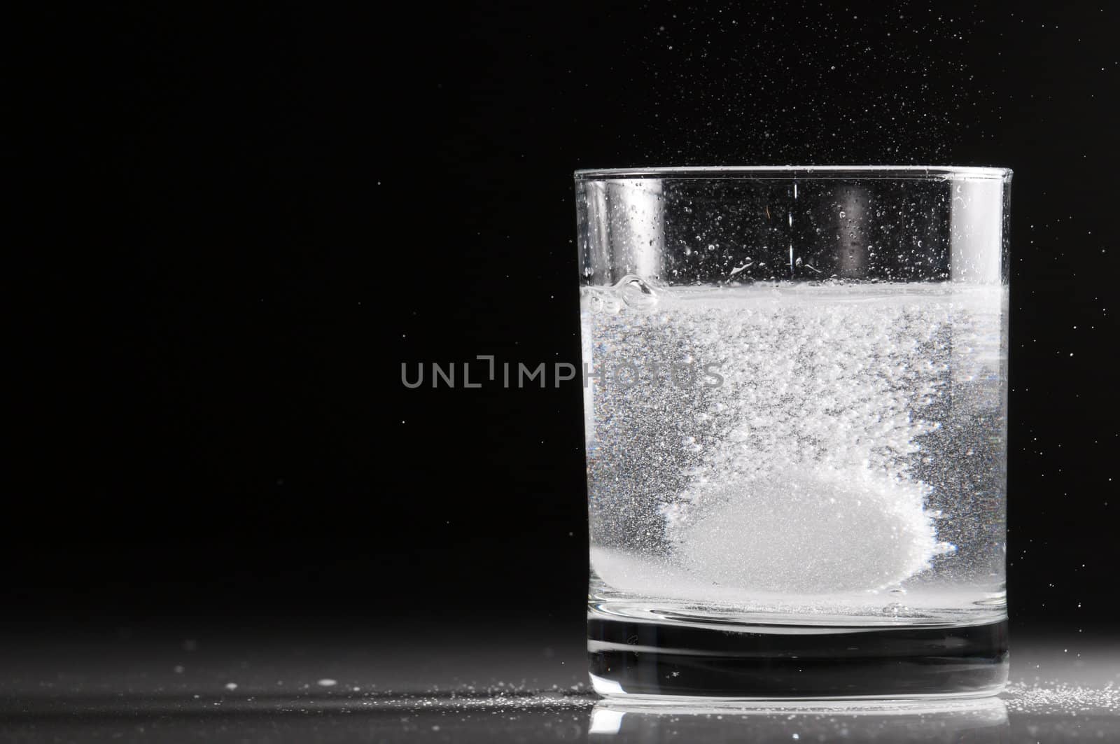 Effervescent pill in a glass of water in backlight