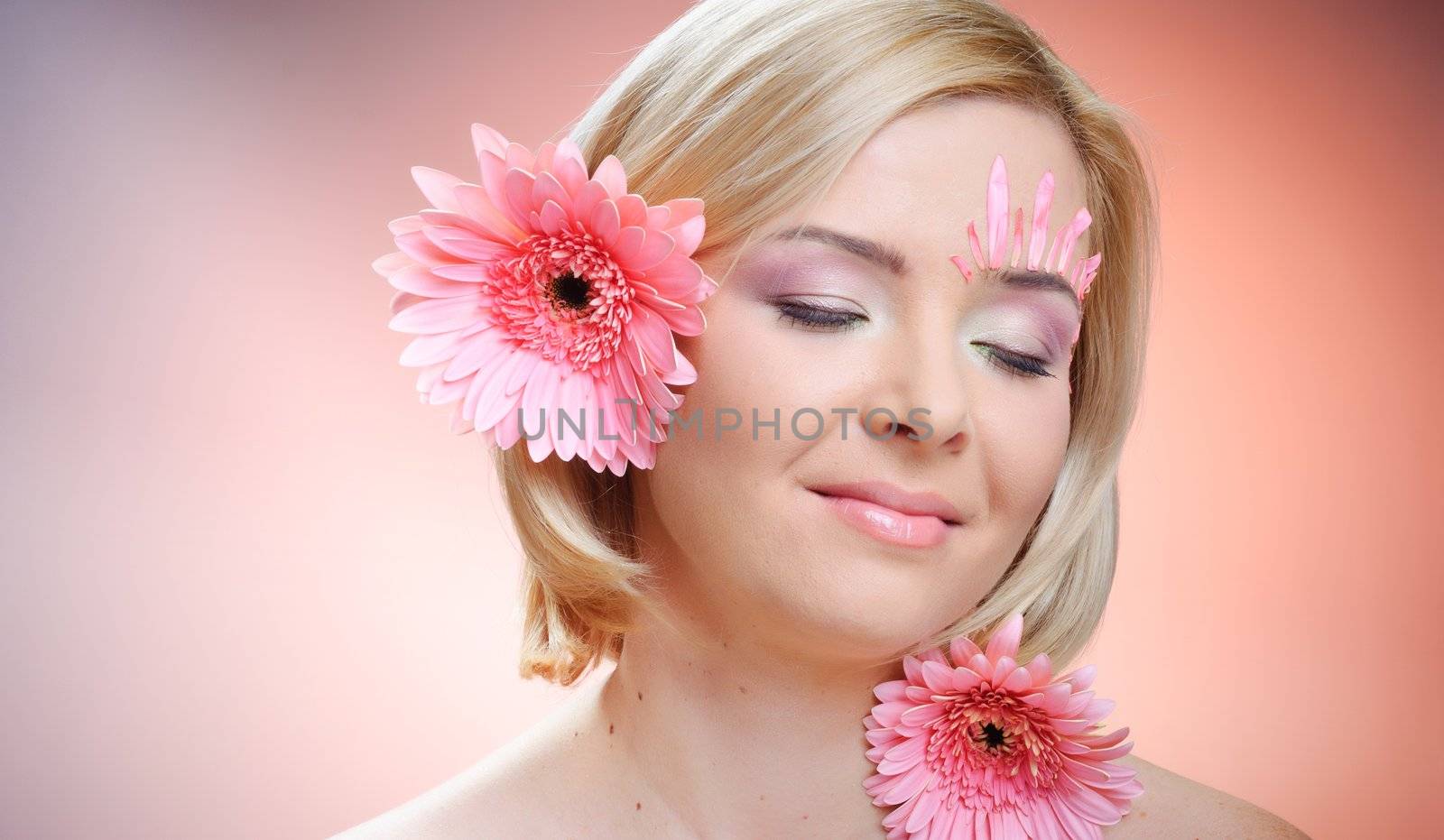 Close-up of woman green eye. Pink flower on background.