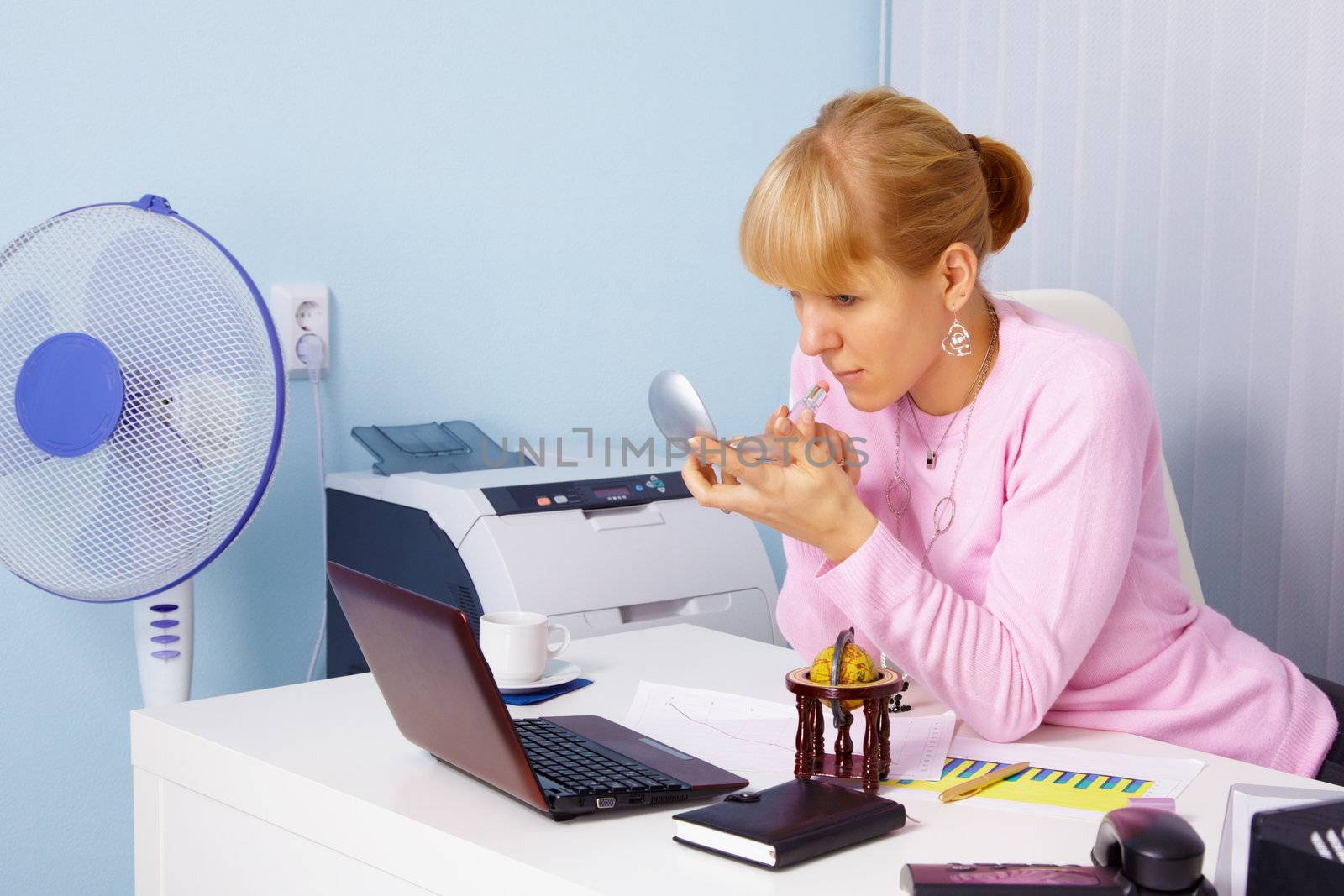 Young woman adjusts makeup in the office