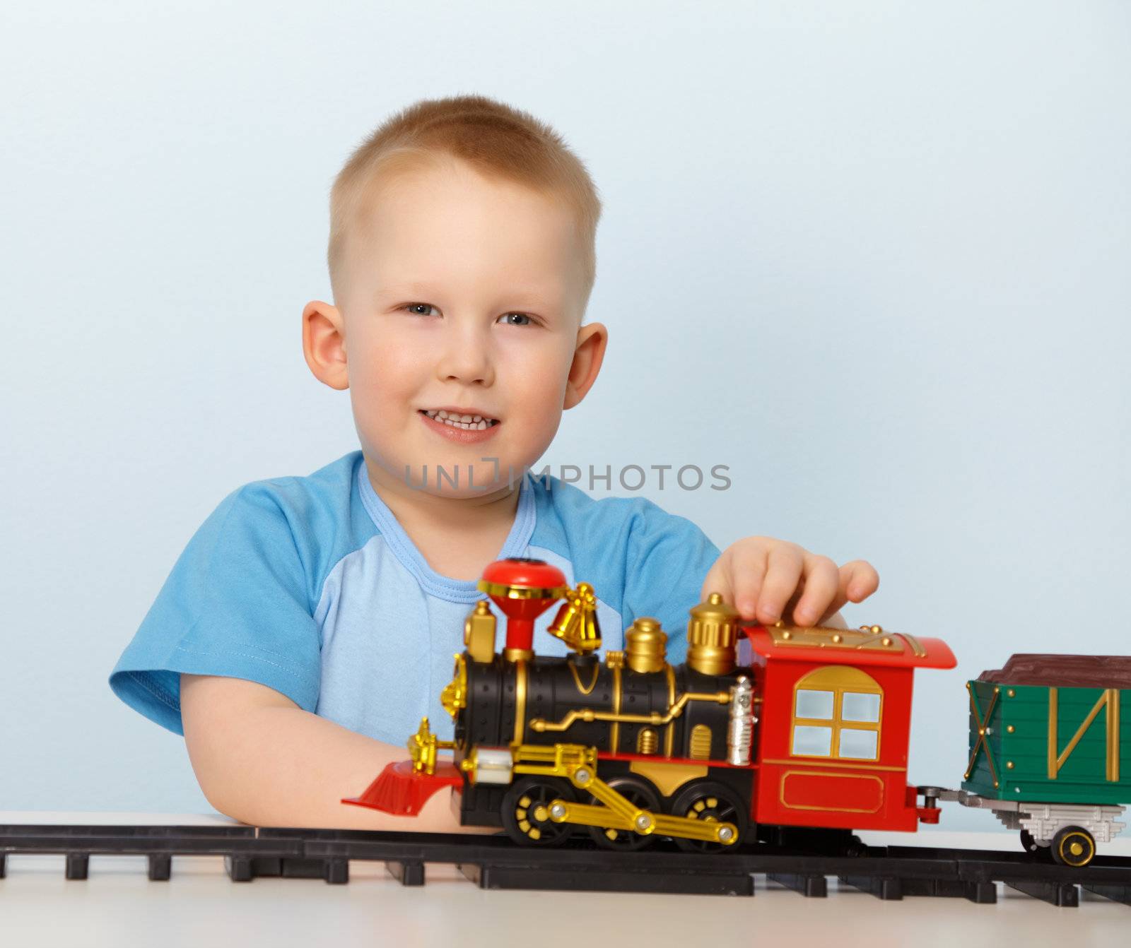 Little boy playing with a toy locomotive on blue background