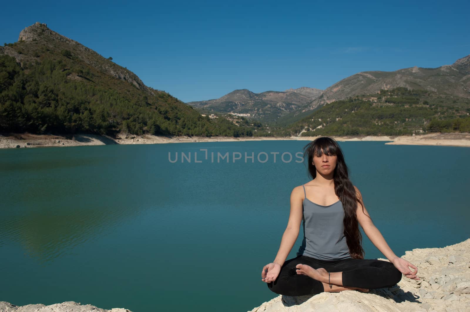 Girl relaxing and doing yoga on the peaceful shores of a lake