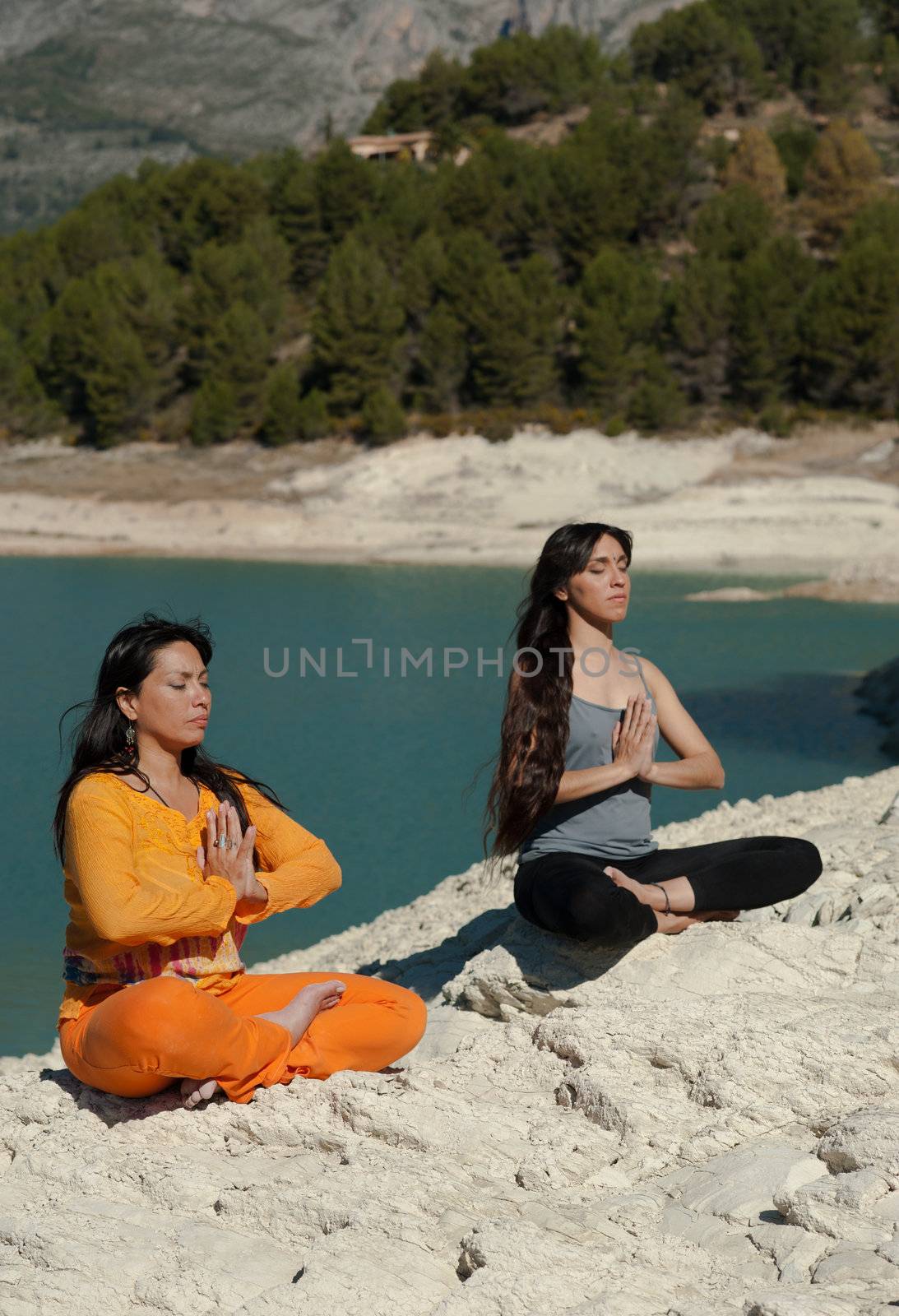 MOther and daughter, yoga at beautiful lakeside setting